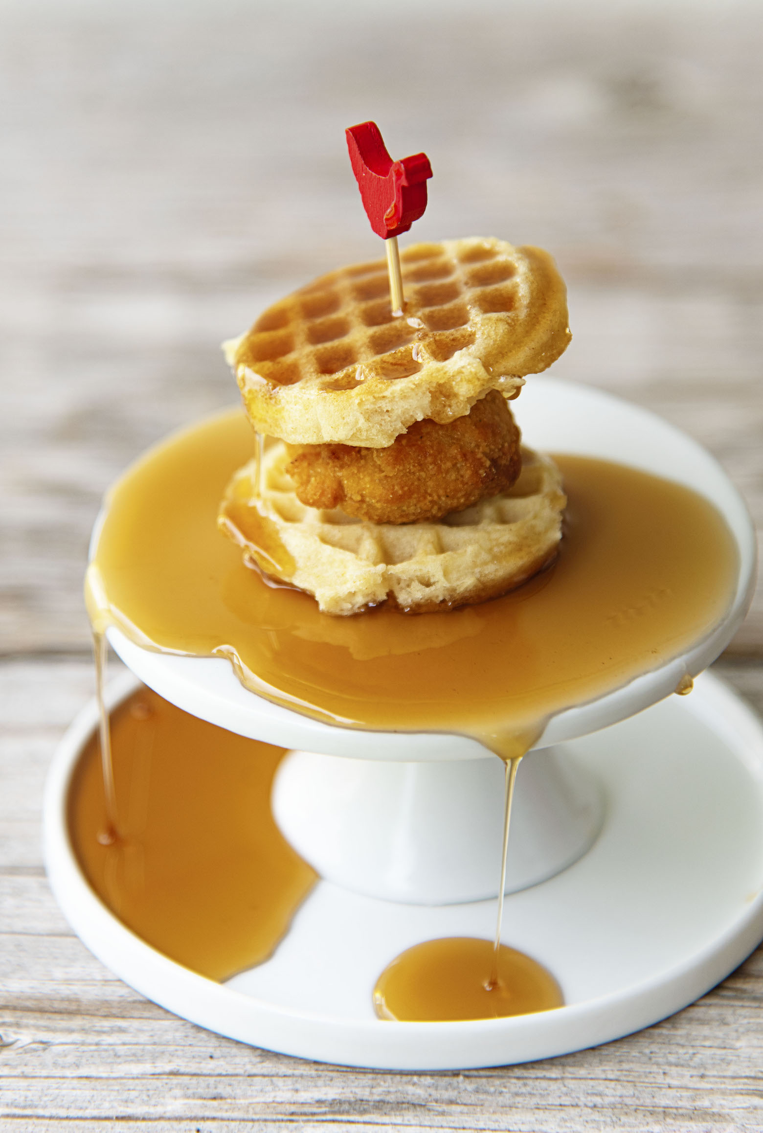 Single Mini Chick’n and Waffle on a mini pedestal covered in syrup.