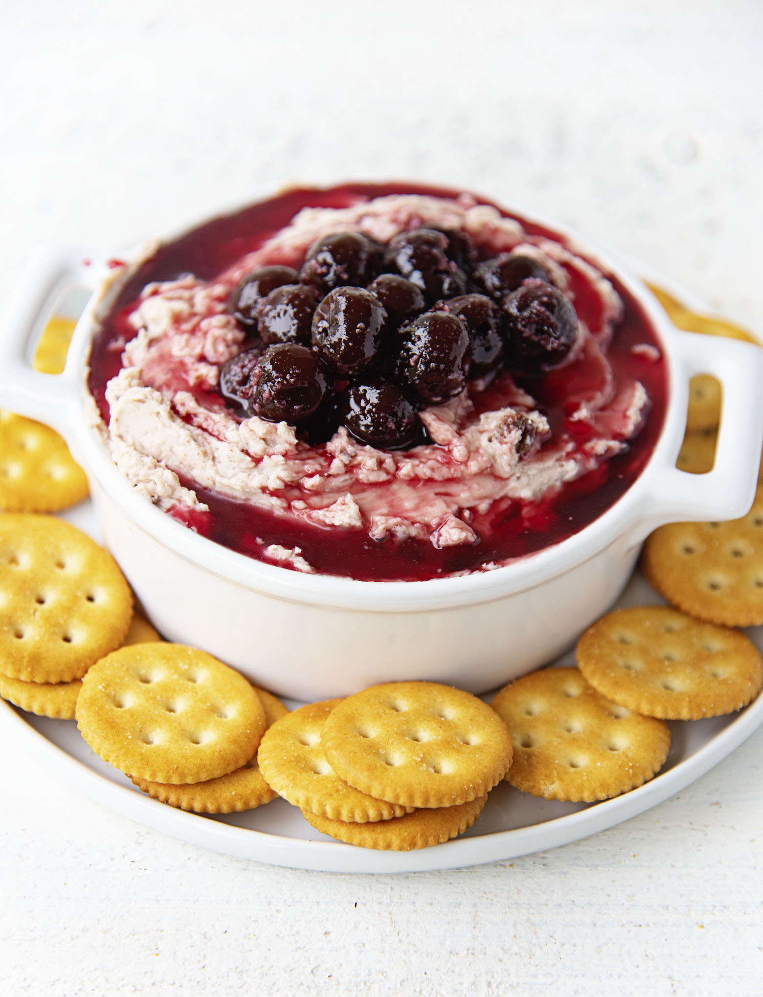 Side view of Cherry Cheddar Cheese Spread in a crock with crackers around it. 