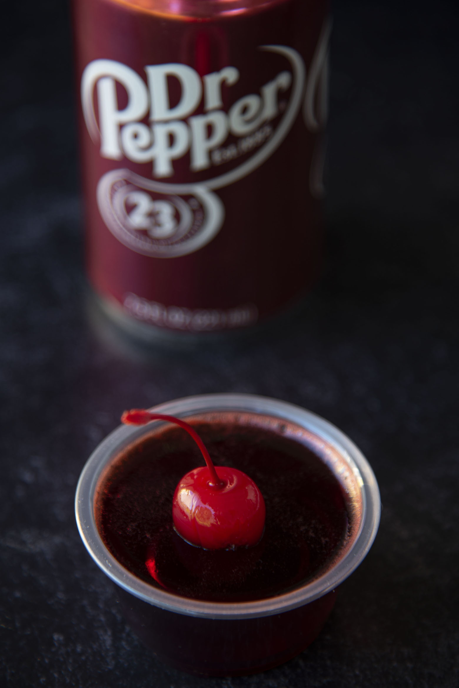 Three quarter shot of single cherry fire pepper jello shot with Dr. Pepper can.
