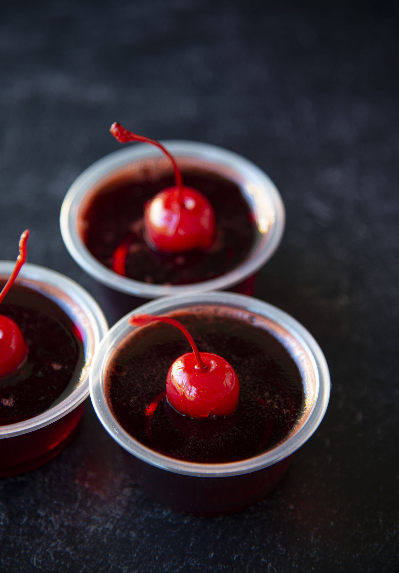 Three quarter shot of three cherry fire pepper jello shots. 