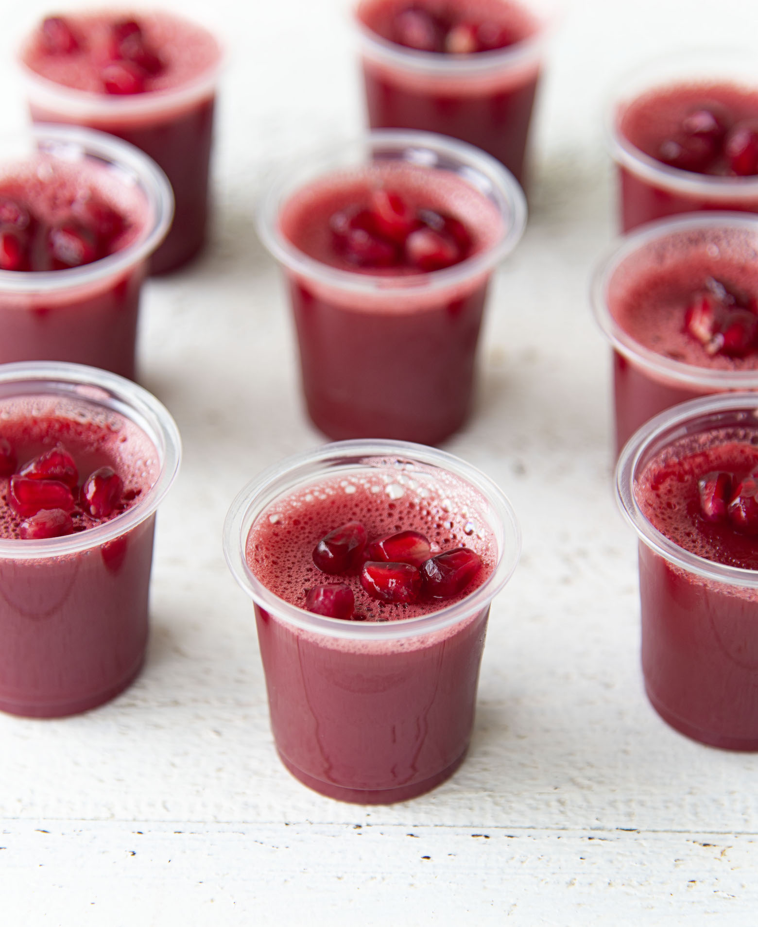 A gathering of several Cherry Pomegranate Moscow Mule Jello Shots topped with pomegranate seeds as garnish.