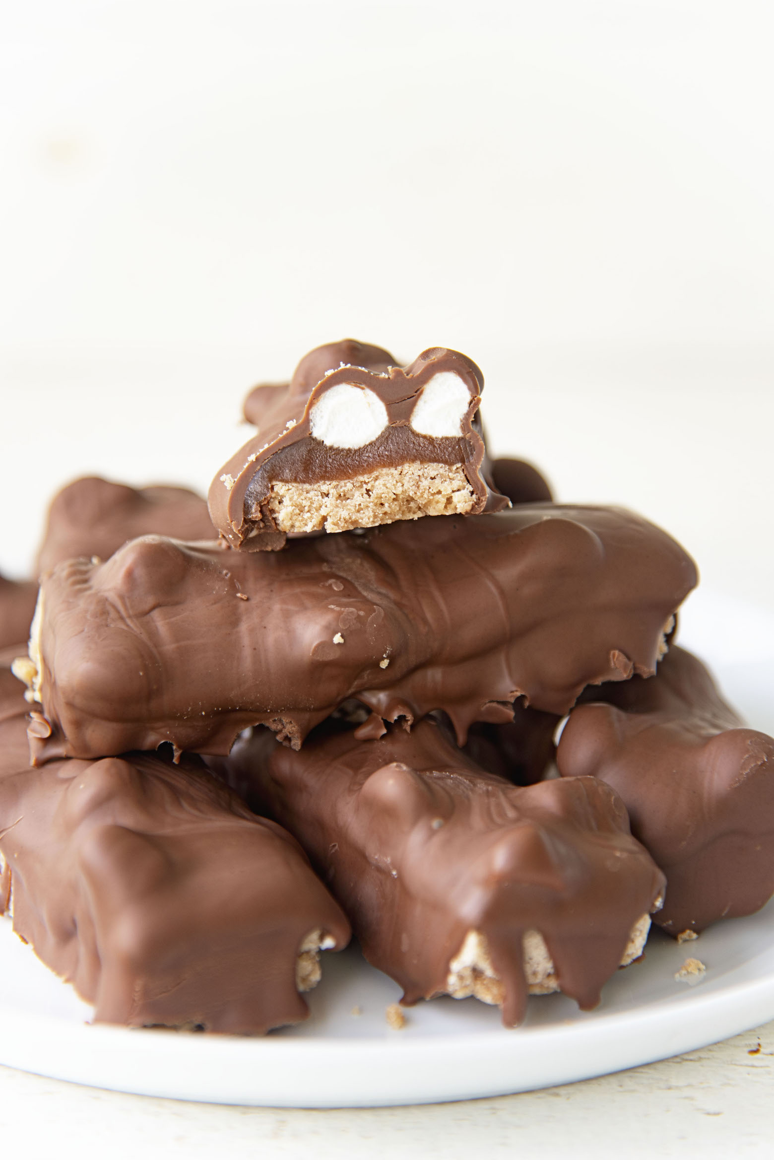 Side view of Hot Chocolate Millionaire Bars stacked on a plate with one cut to see the inside. 