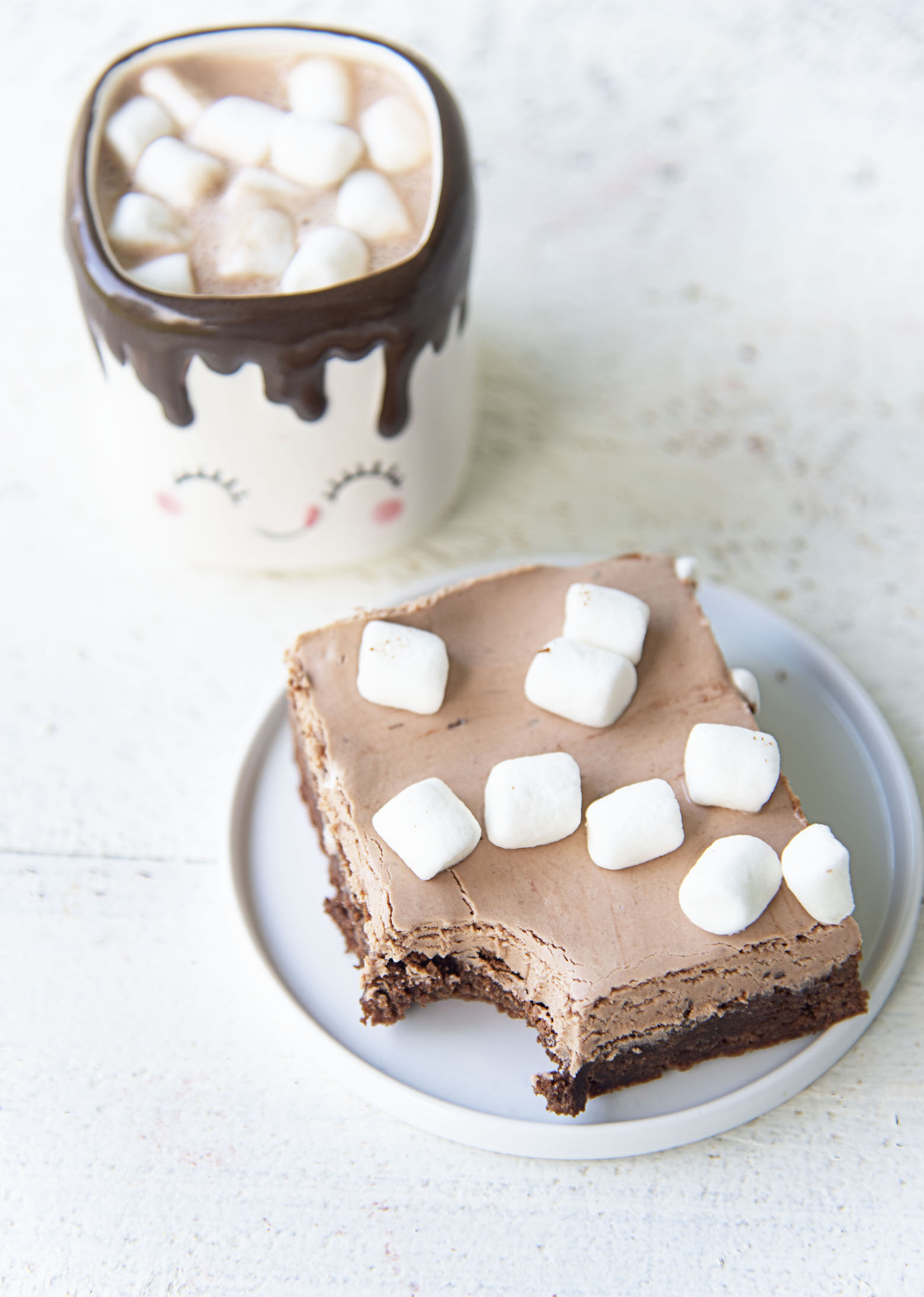 Three quarter shot of a hot chocolate nougat brownie on a plate with a bite taken out of the brownie. 