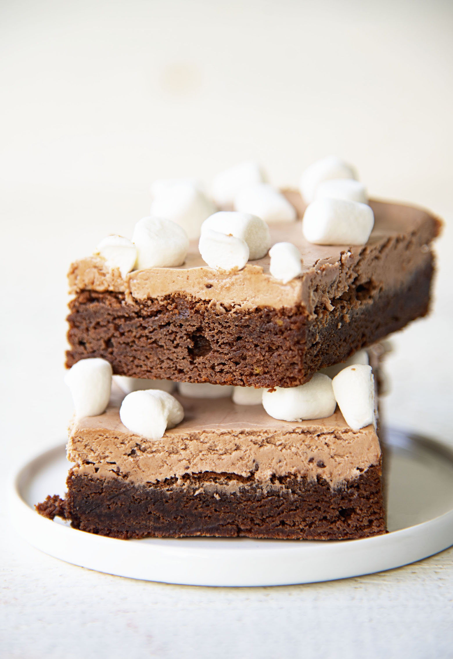 Two  brownies stacked on top of each other on a plate.