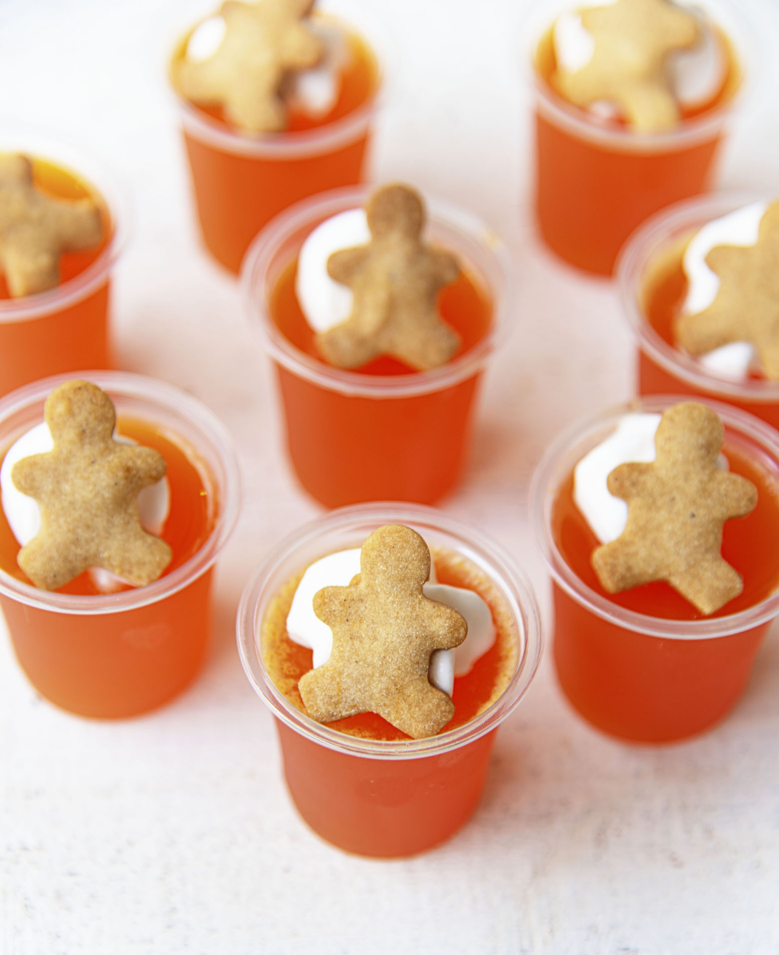 Three quarter shot of the jello shots with the whipped cream and mini gingerbread men being the main focus.