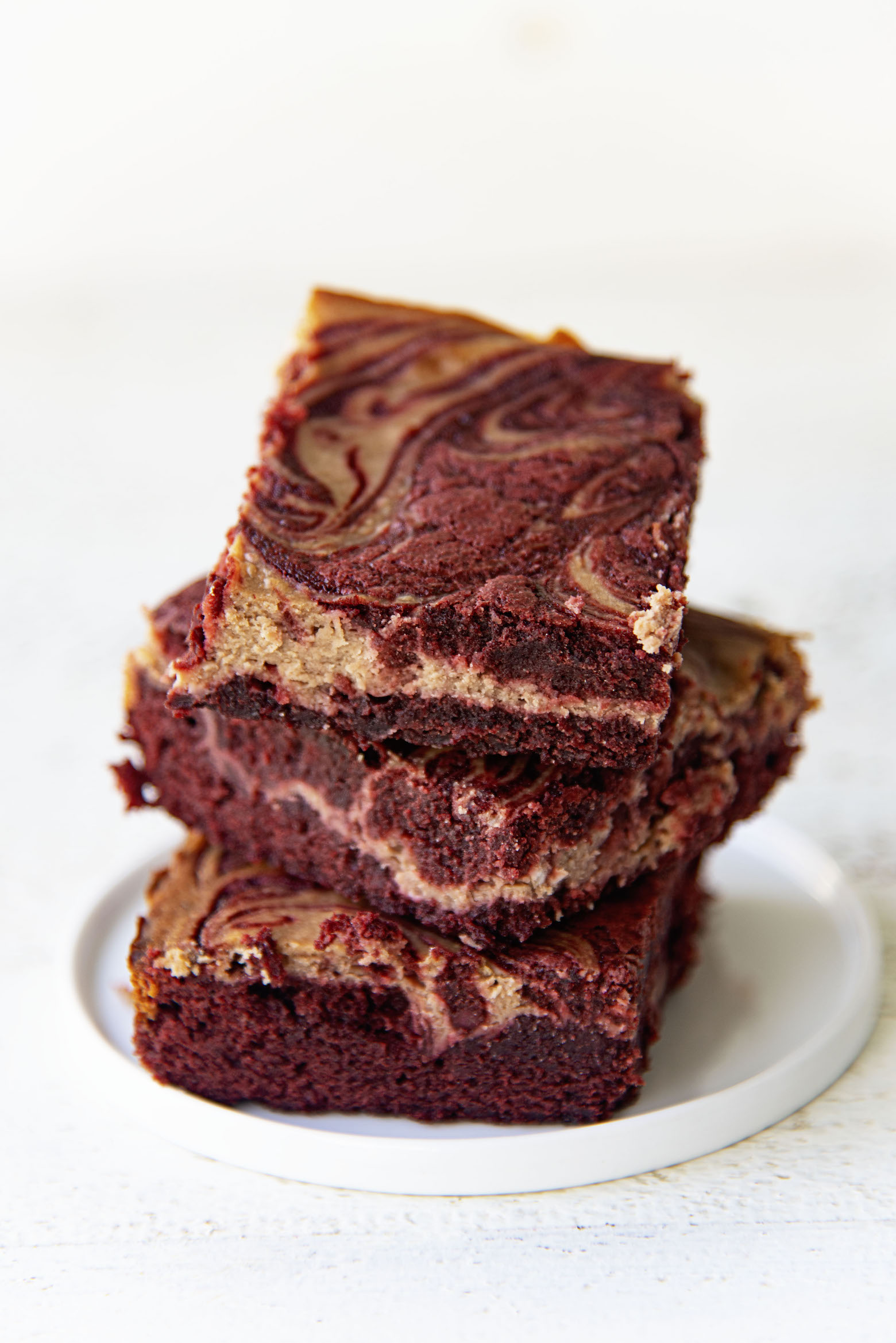 Stack of three Red Velvet Hot Chocolate Brownies on a small plate.