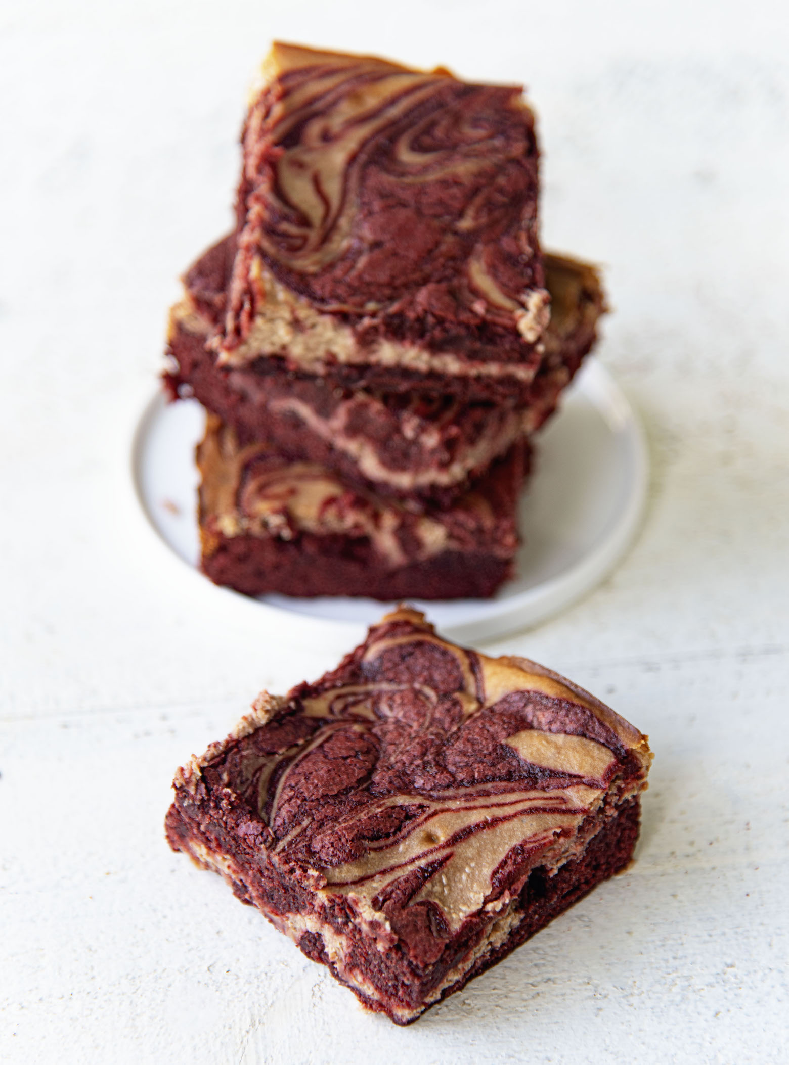 Single Red Velvet Hot Chocolate Brownie in front of three brownies stacked up behind it. 