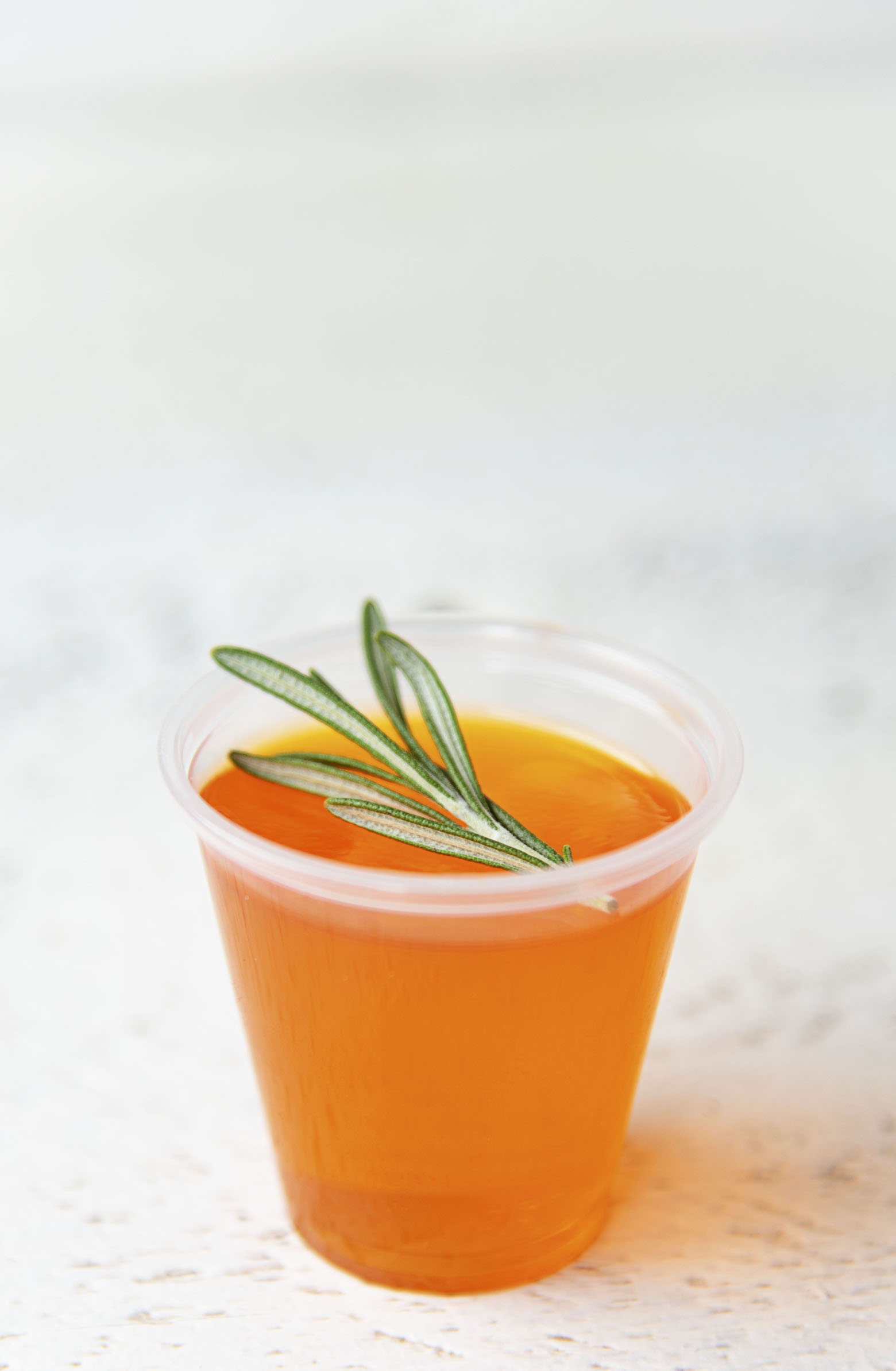Single Winter Sun Jello Shot with upclose shot of the rosemary garnish.