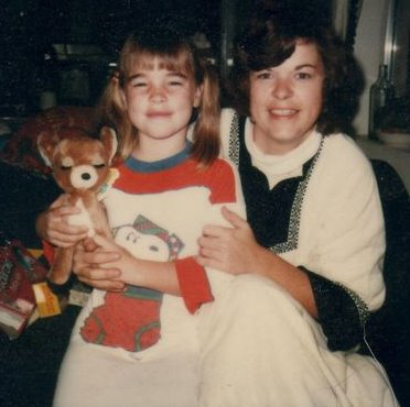 Mom and me at Christmas while I hold a stuffed reindeer.