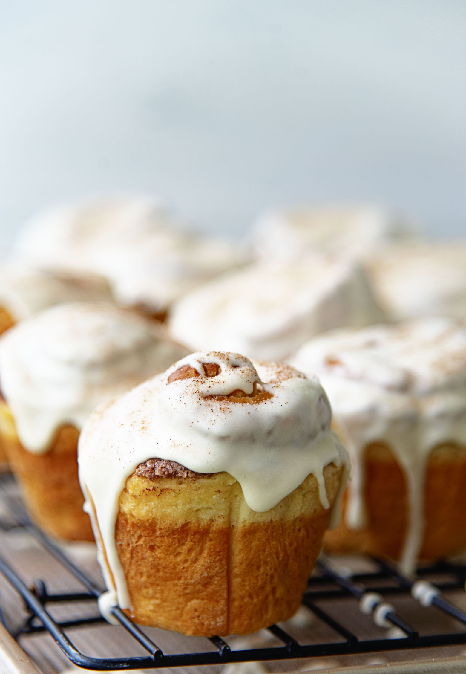 Several Bourbon Eggnog Breakfast Buns on a wire rack with the first bun being the focus point