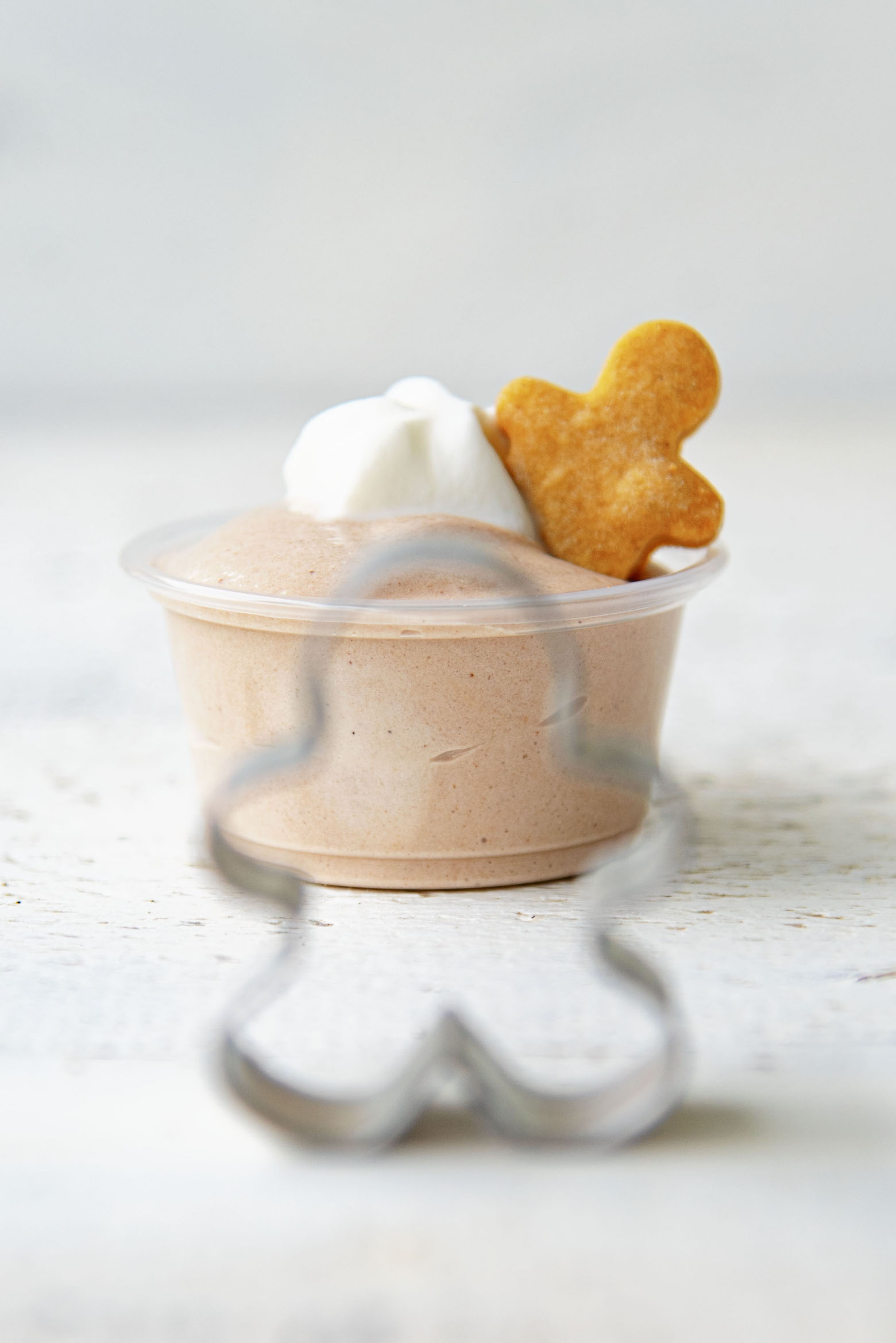 Chocolate Gingerbread Pudding Shots with gingerbread man cookie cutter in front of it. 