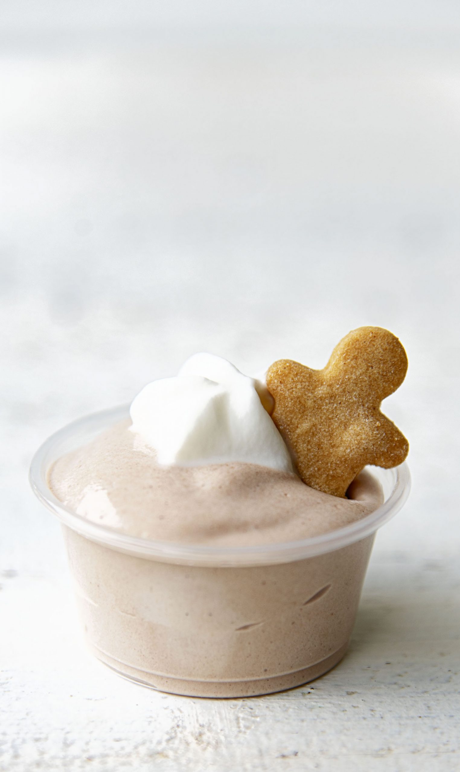 Close up side view of a single pudding shot with the gingerbread man cookie peeking out of it 