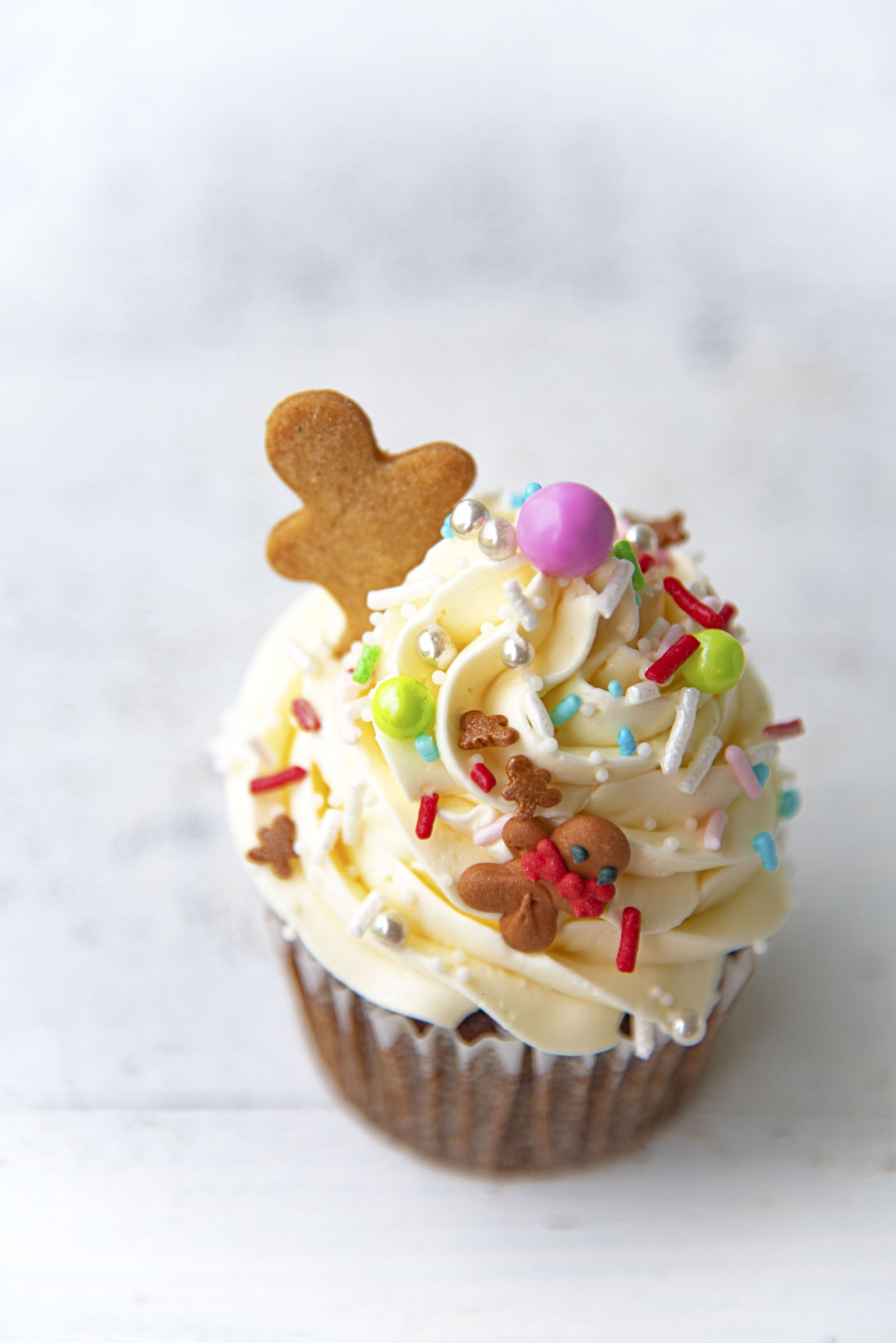 Overhead shot of single Gingerbread White Chocolate Cupcake with focus on the sprinkles.