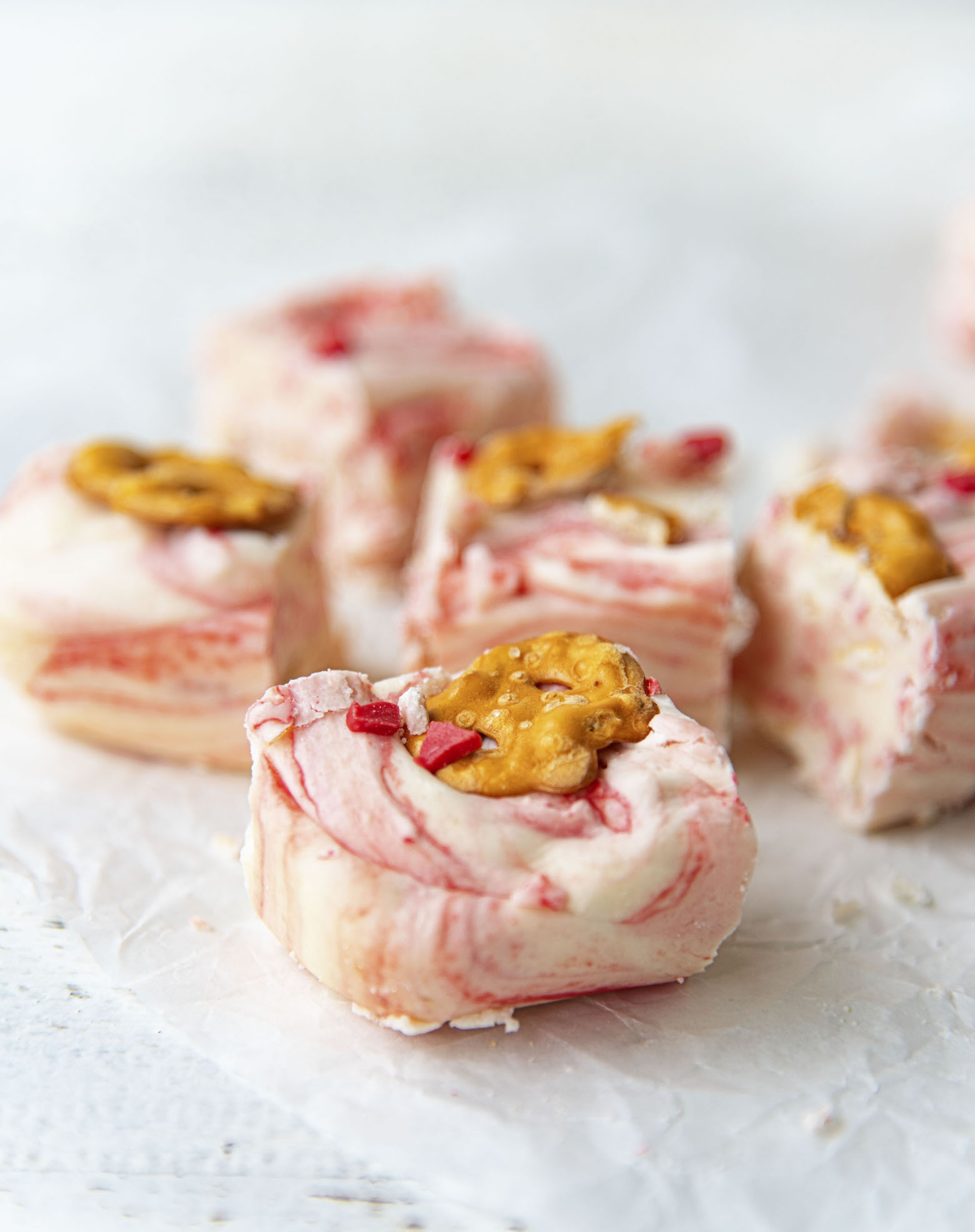 Four pieces of the red and white marbled fudge close up. 