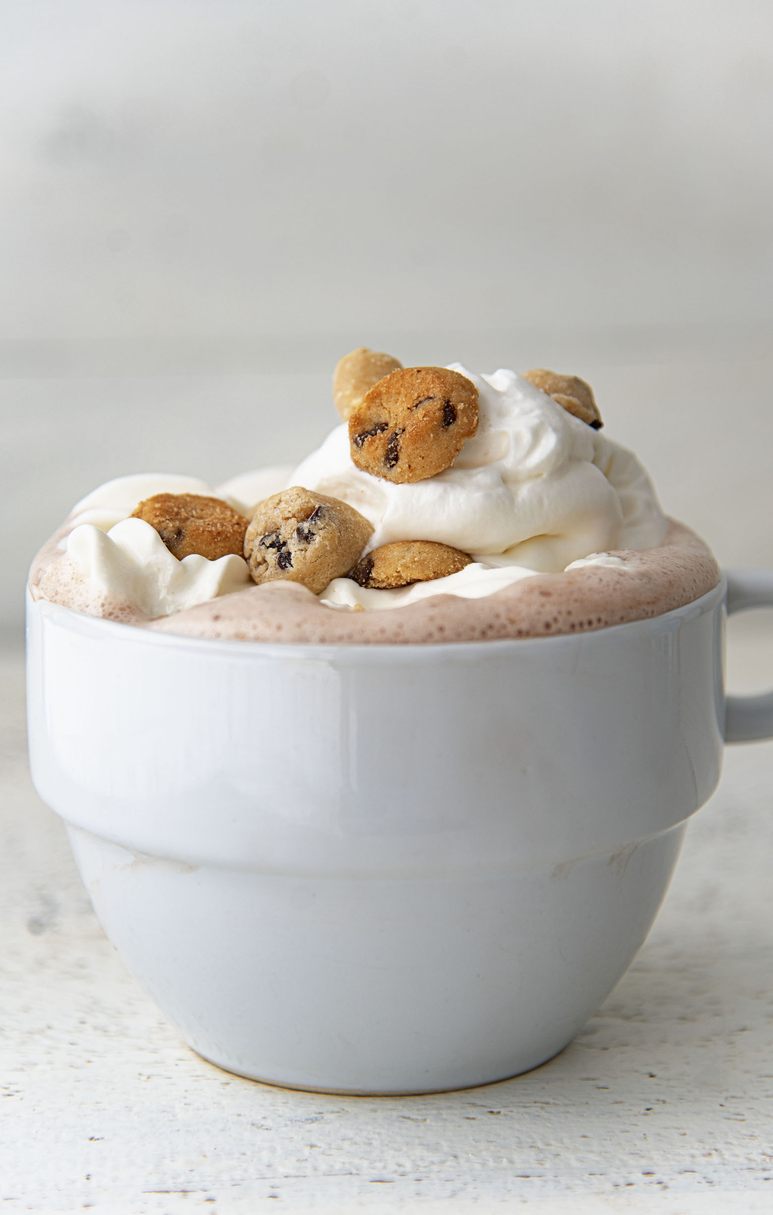 Side view of Cookie Dough Hot Cocoa with focus on whipped cream and the toppings. 