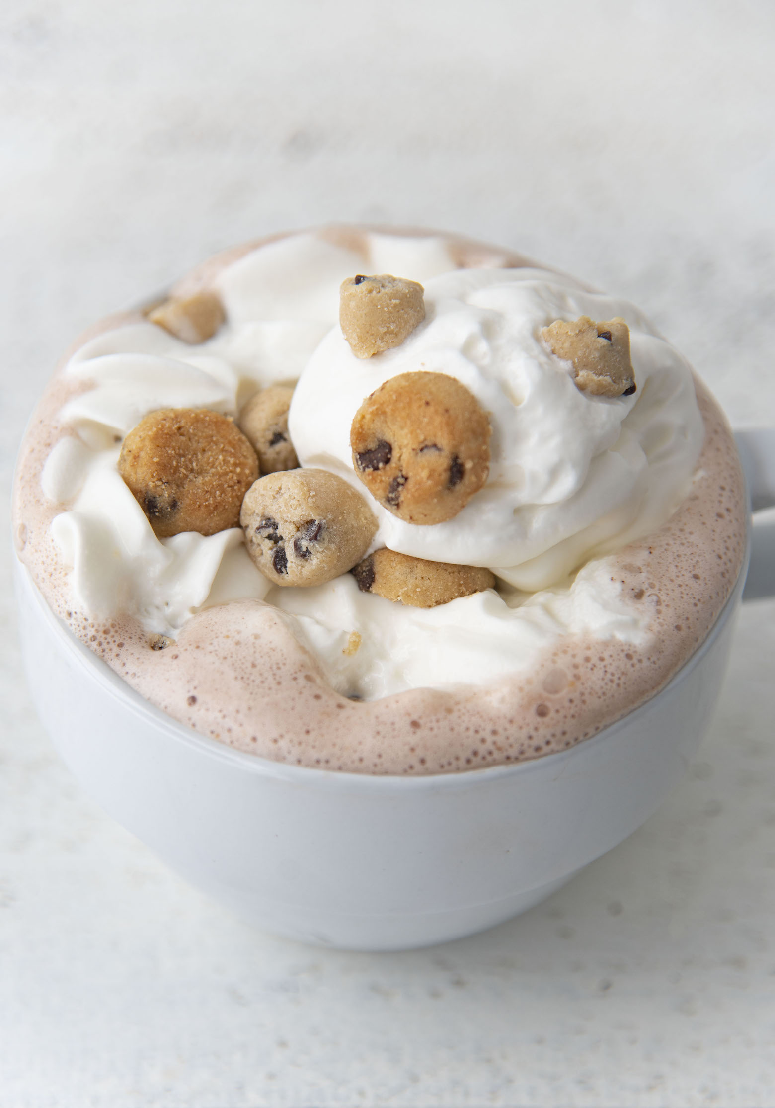 Shot of the Cookie Dough Hot Cocoa covered in whipped cream and cookie dough pieces. 