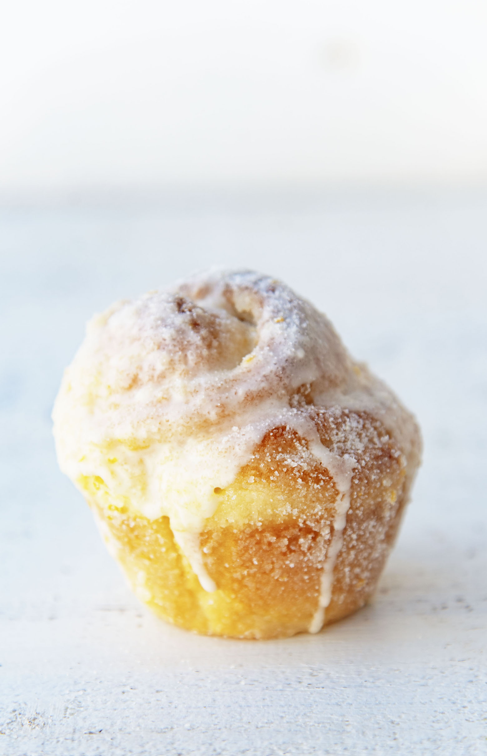 Side view of single Mimosa Sugared Sweet Roll with glaze dripping down