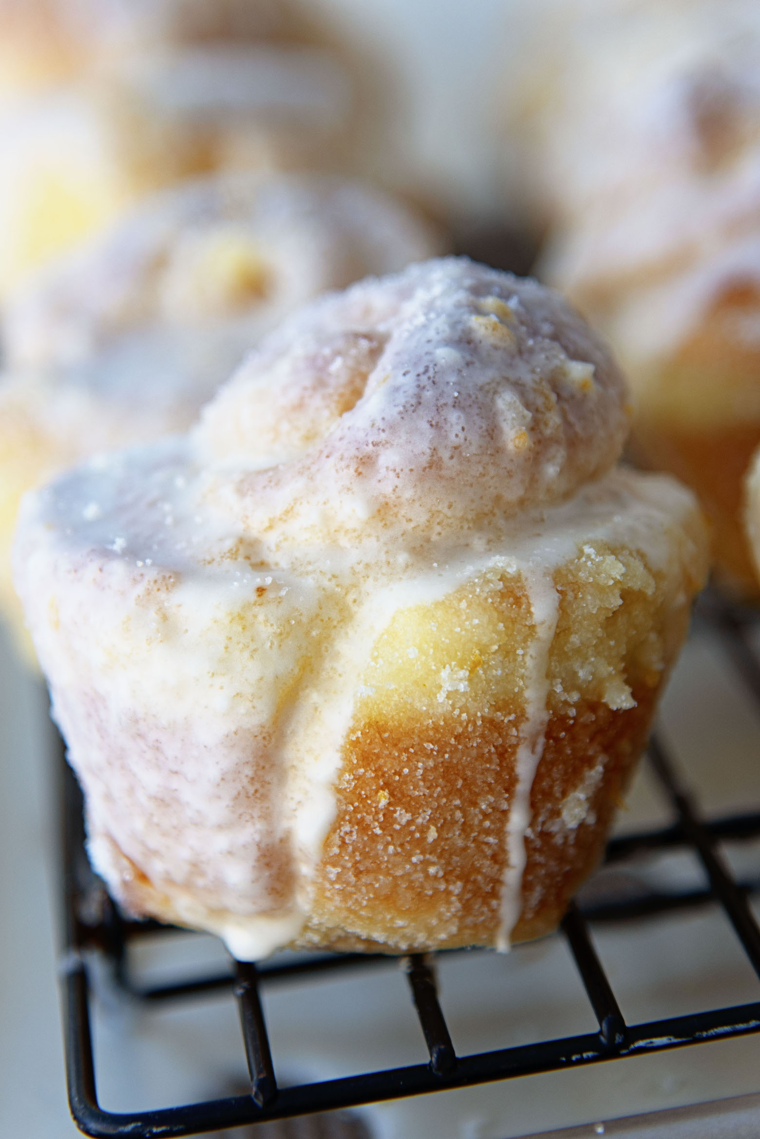Row of Mimosa Sugared Sweet Rolls on a wire rack with the glaze down below. 