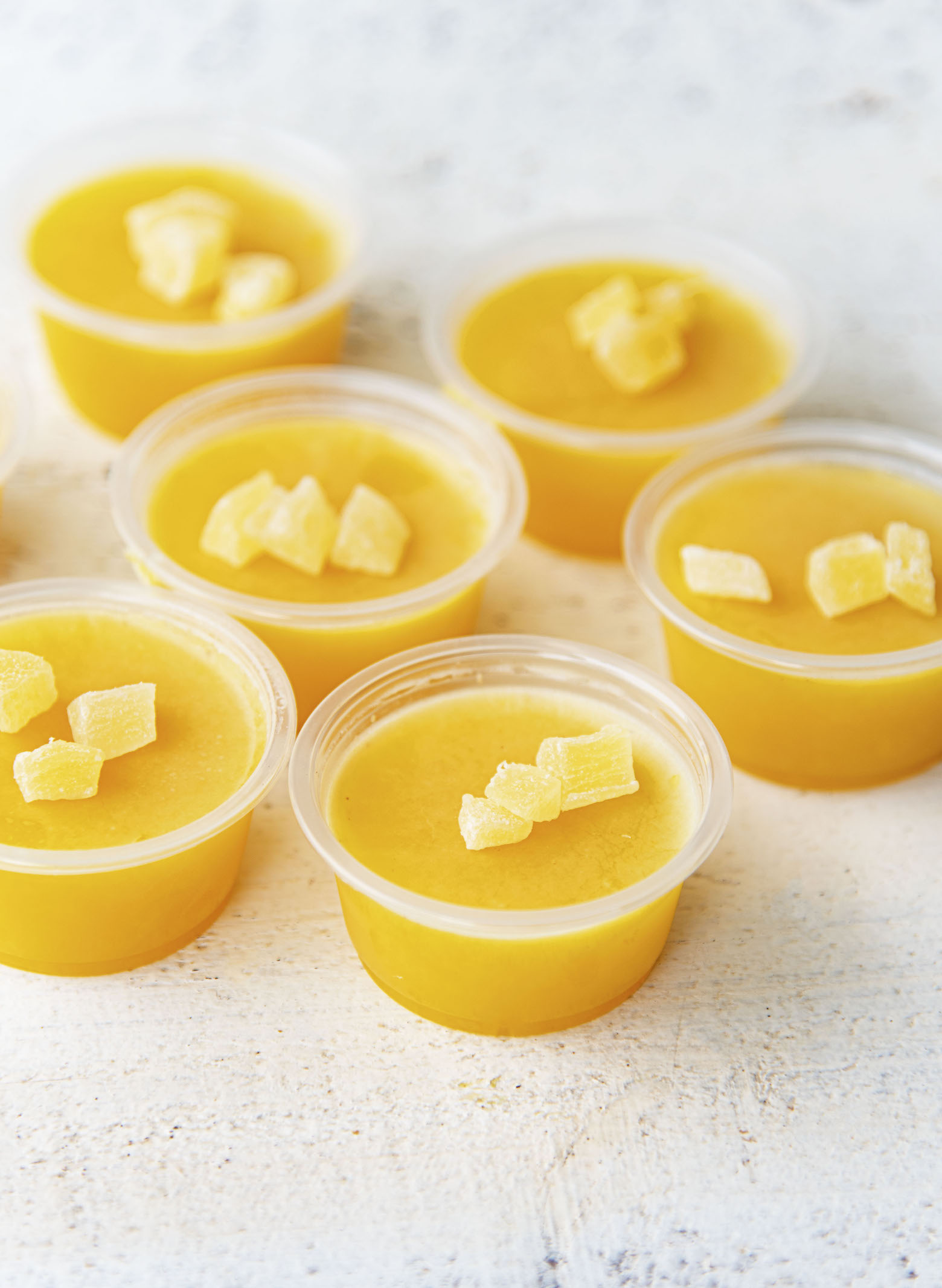 Grouping of Painkiller Cocktail Jello Shots all topped with dried pineapple pieces.
