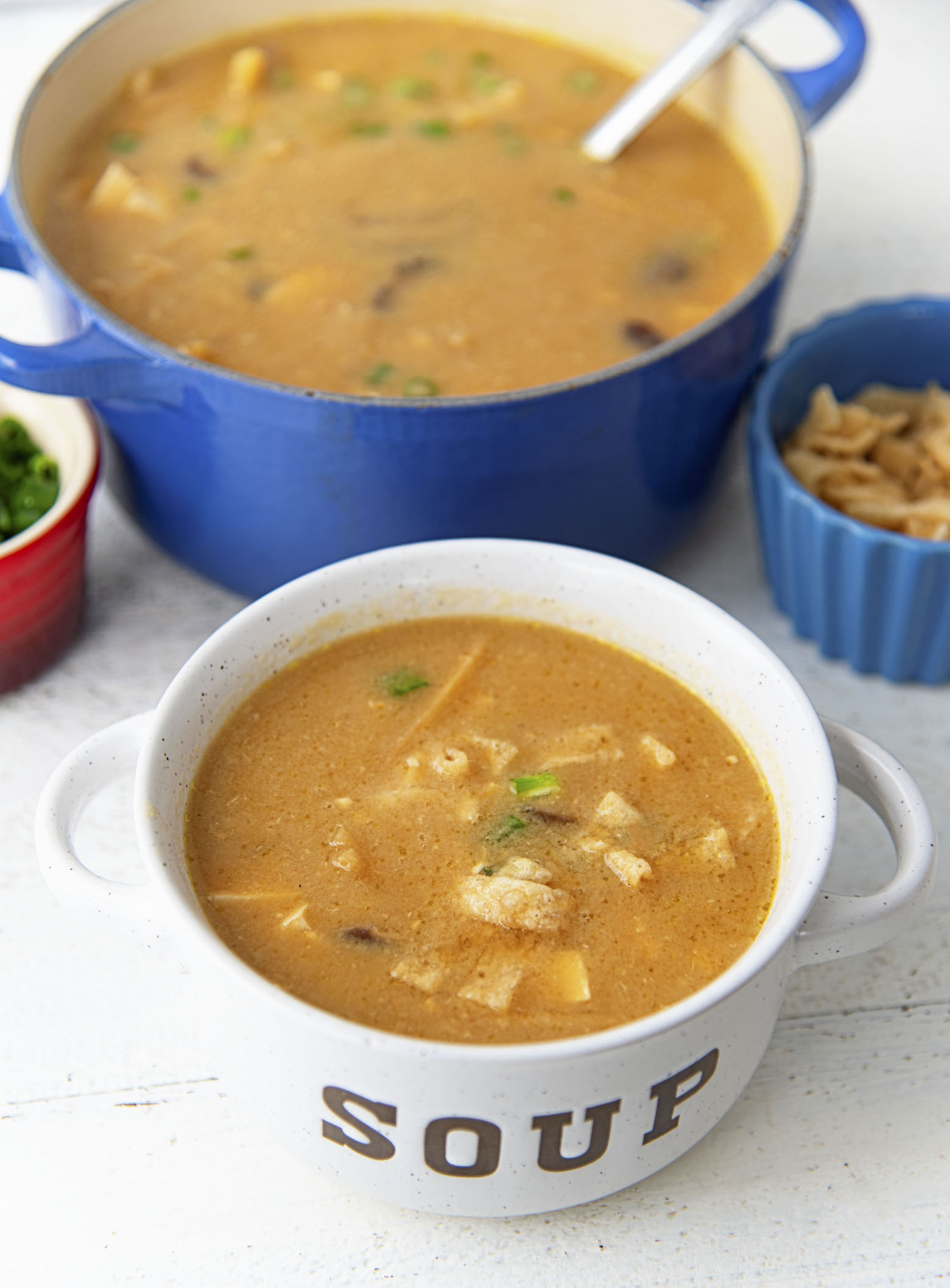 Bowl of hot and sour soup with larger pot in the back. 