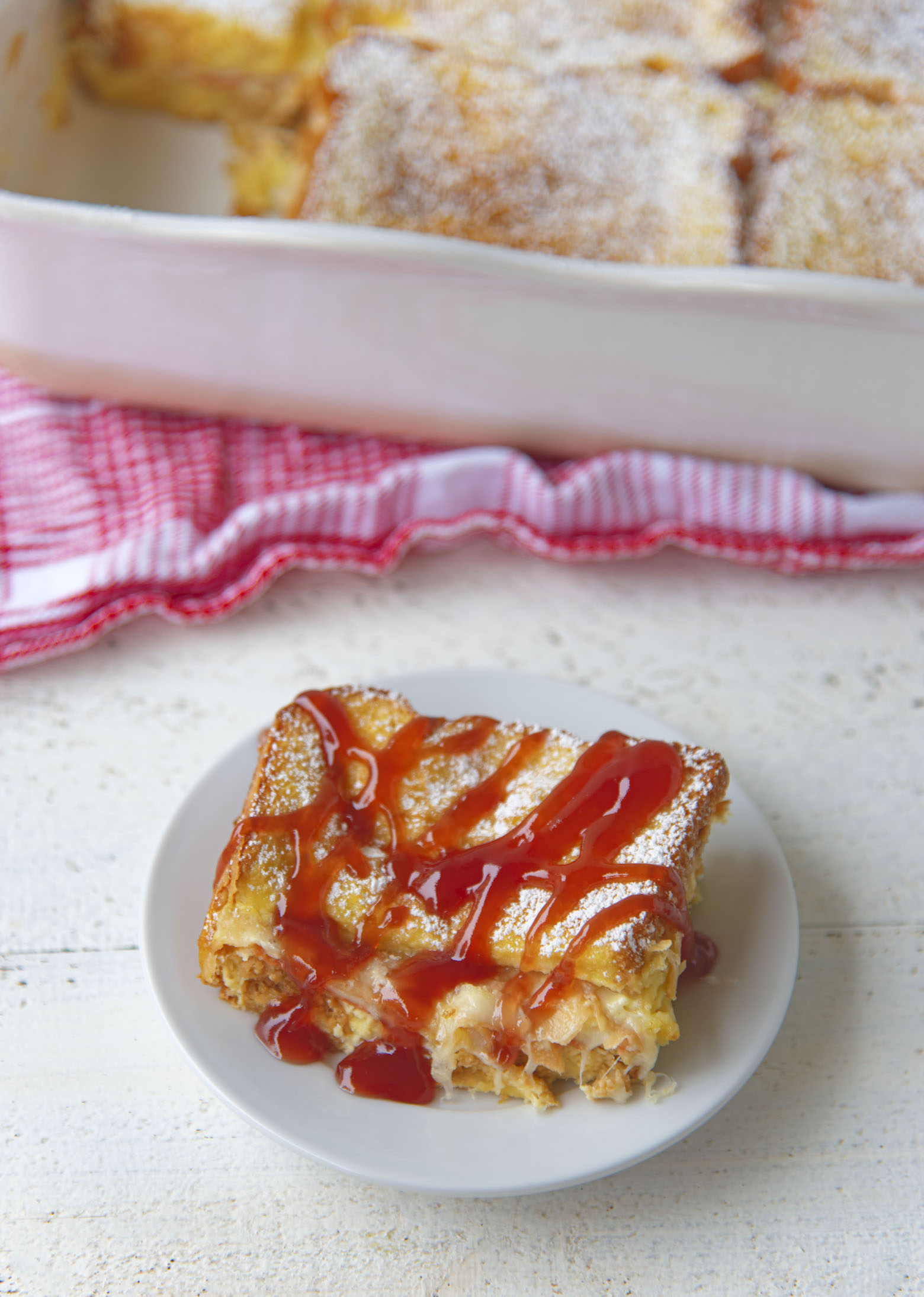 Slice of Vegetarian Monte Cristo Casserole with Strawberry Jam drizzled on it. 