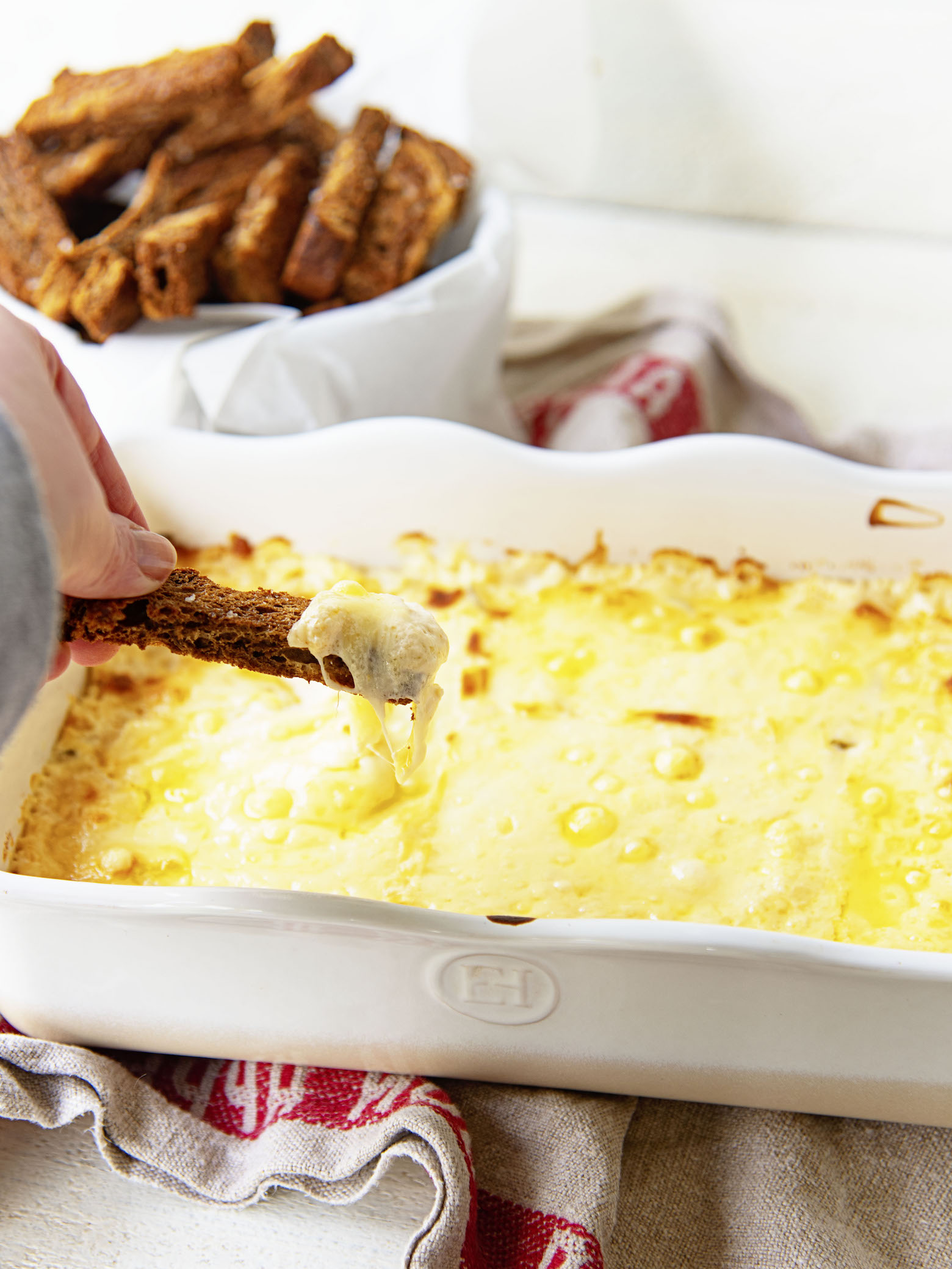 Dipping a rye bread crouton in the dish of Vegetarian Reuben Cheese Dip. 