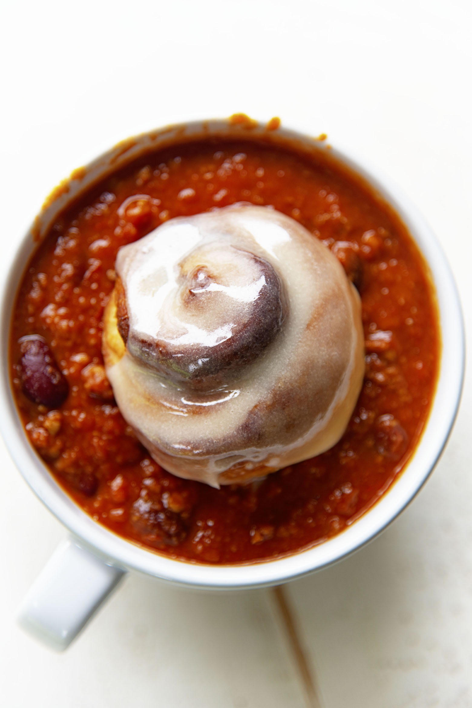 Overhead shot of cinnamon roll sitting in a bowl of chili.