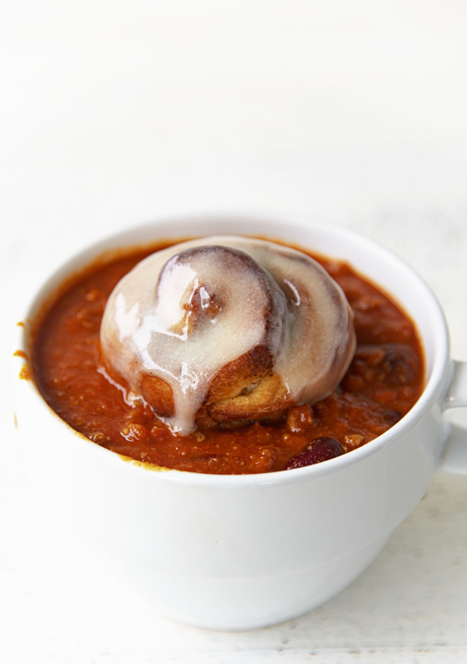 Cinnamon roll sitting in a bowl of chili. 