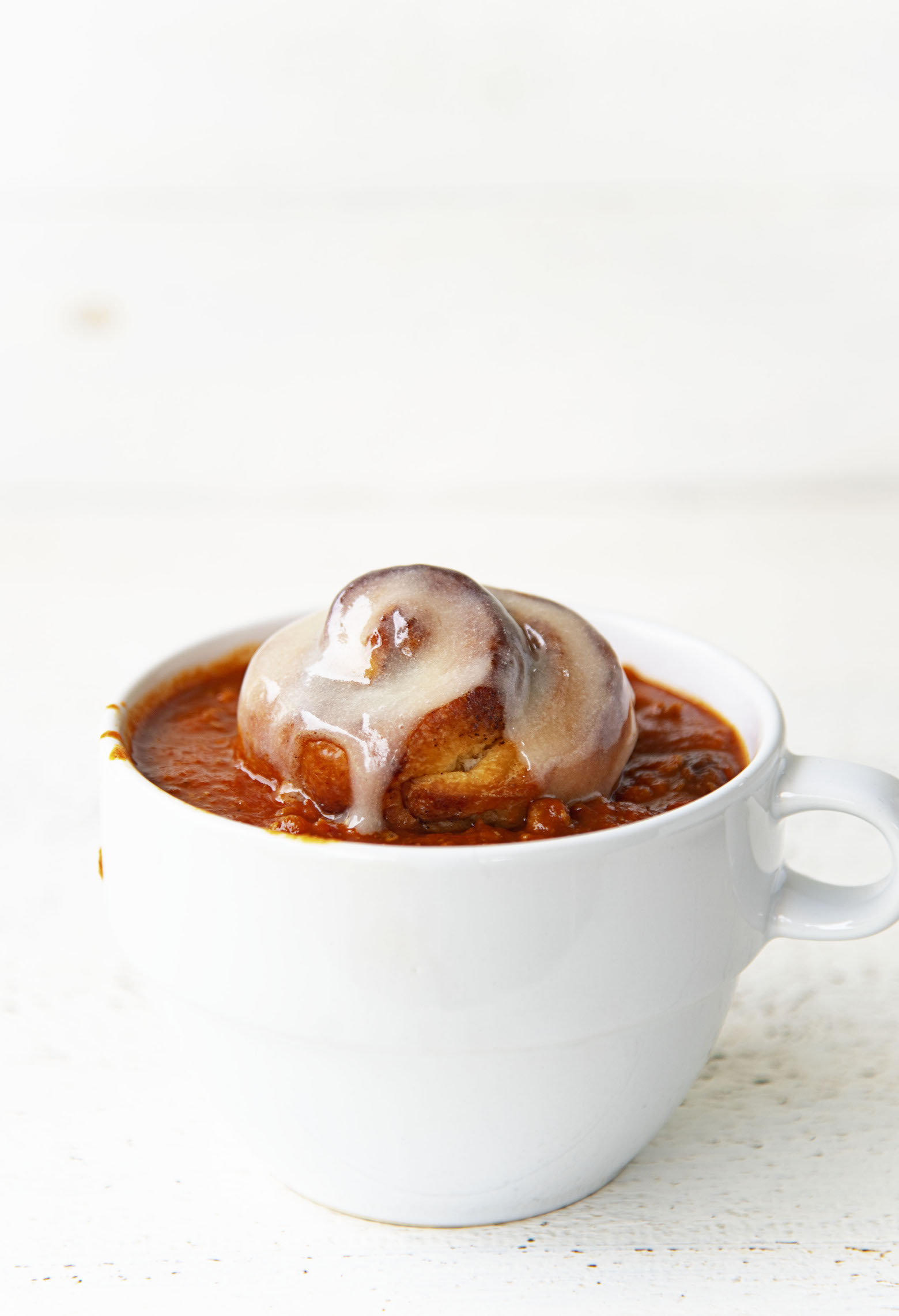 Side view of the chili with cinnamon roll in the middle of the bowl. 