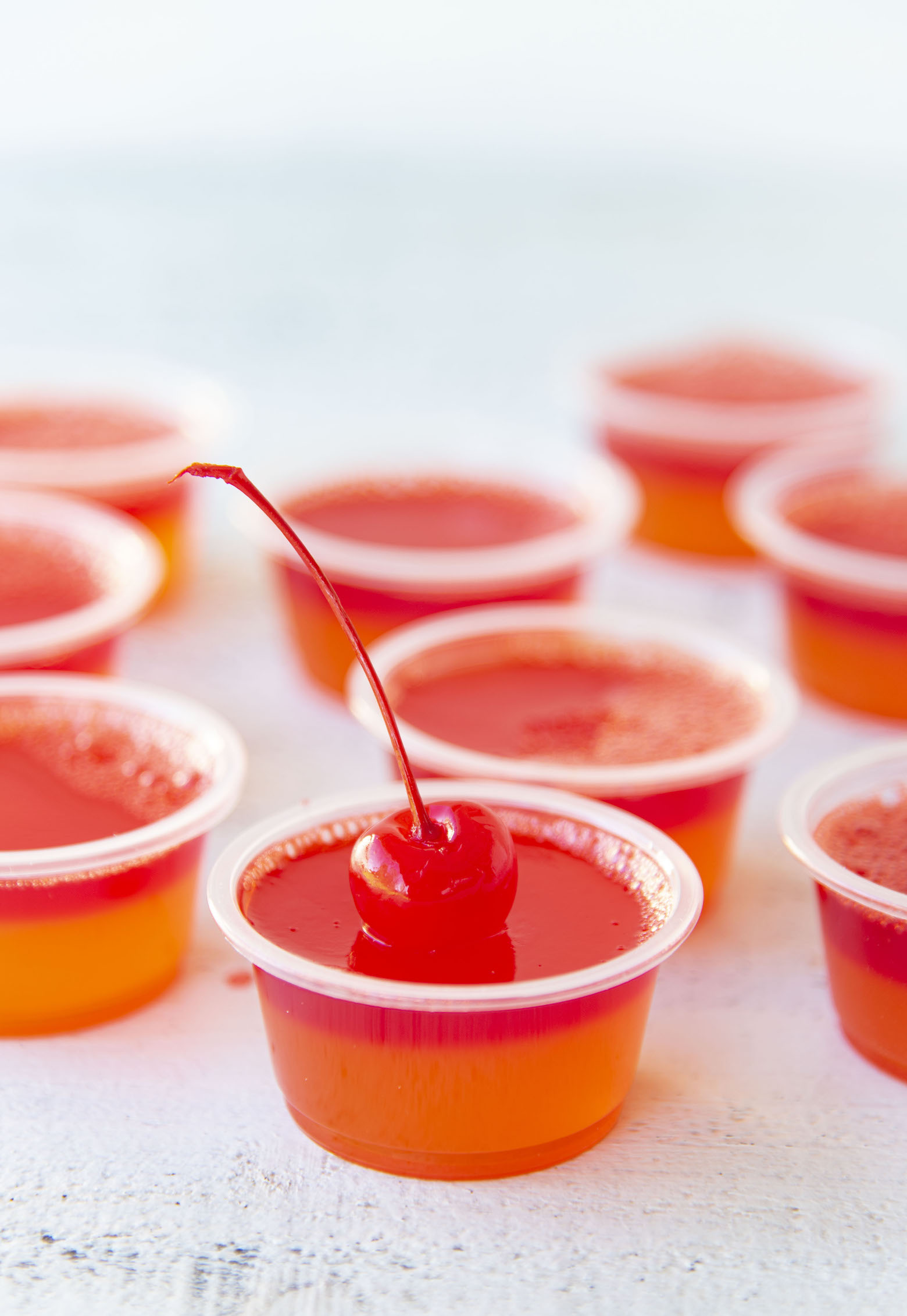 Side view of Hurricane Cocktail Jello Shots with focus on first shot with the cherry. 