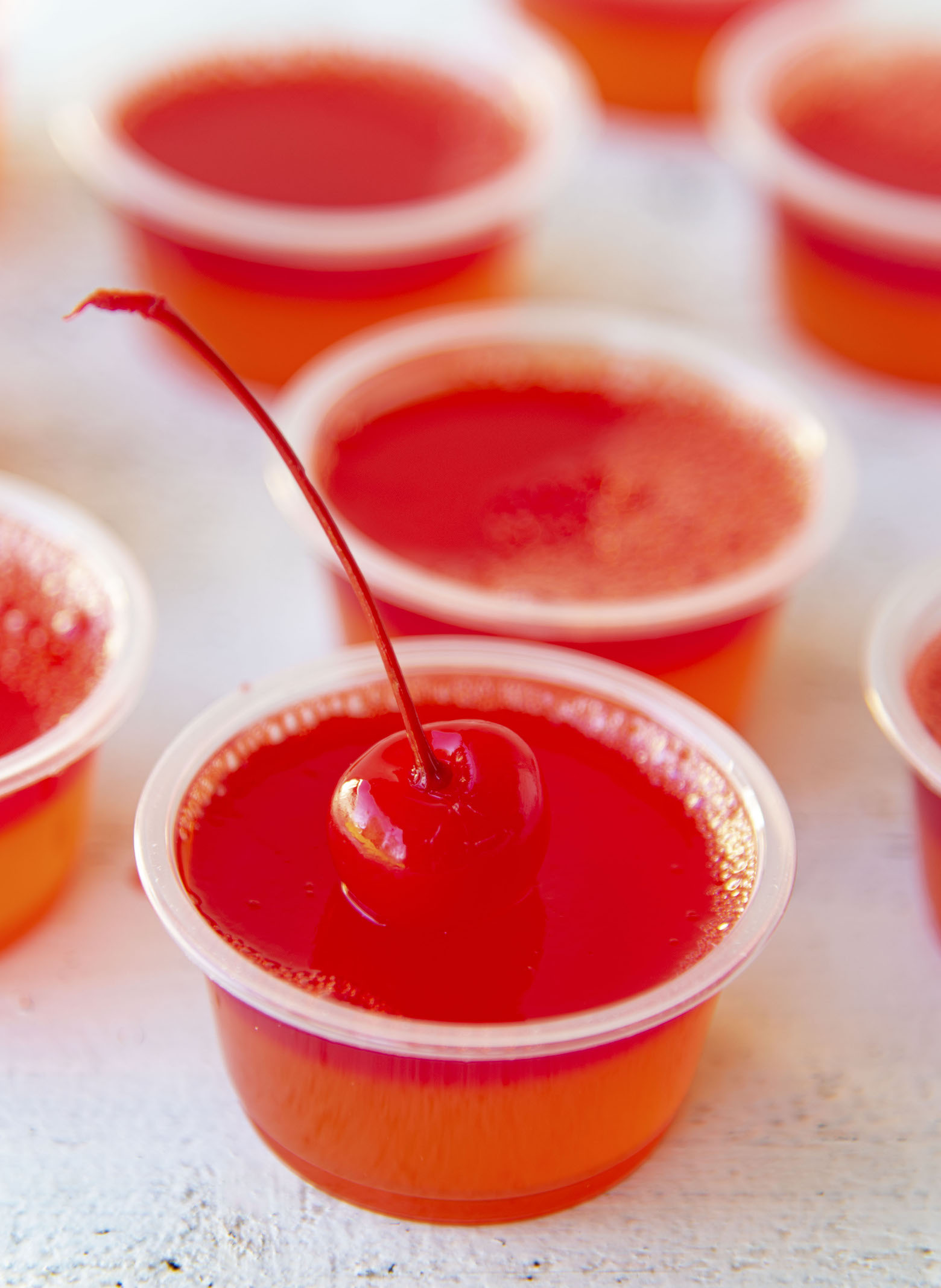 Close up of a Hurricane Cocktail Jello Shot with a cherry on top. 