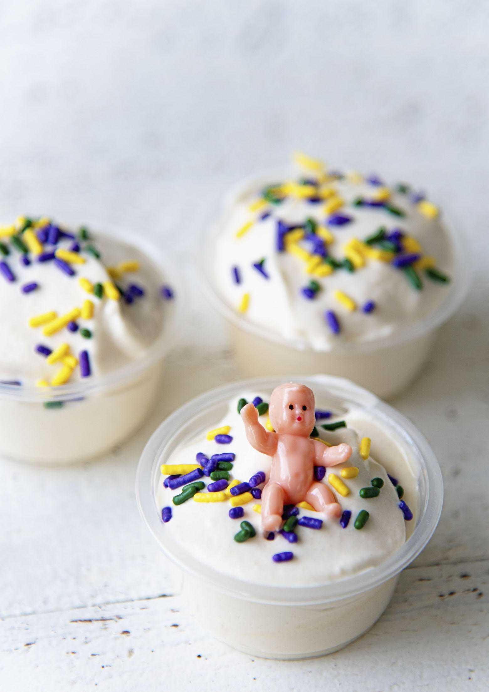 Three pudding shots with first shot in focus with the sprinkles and baby on top.