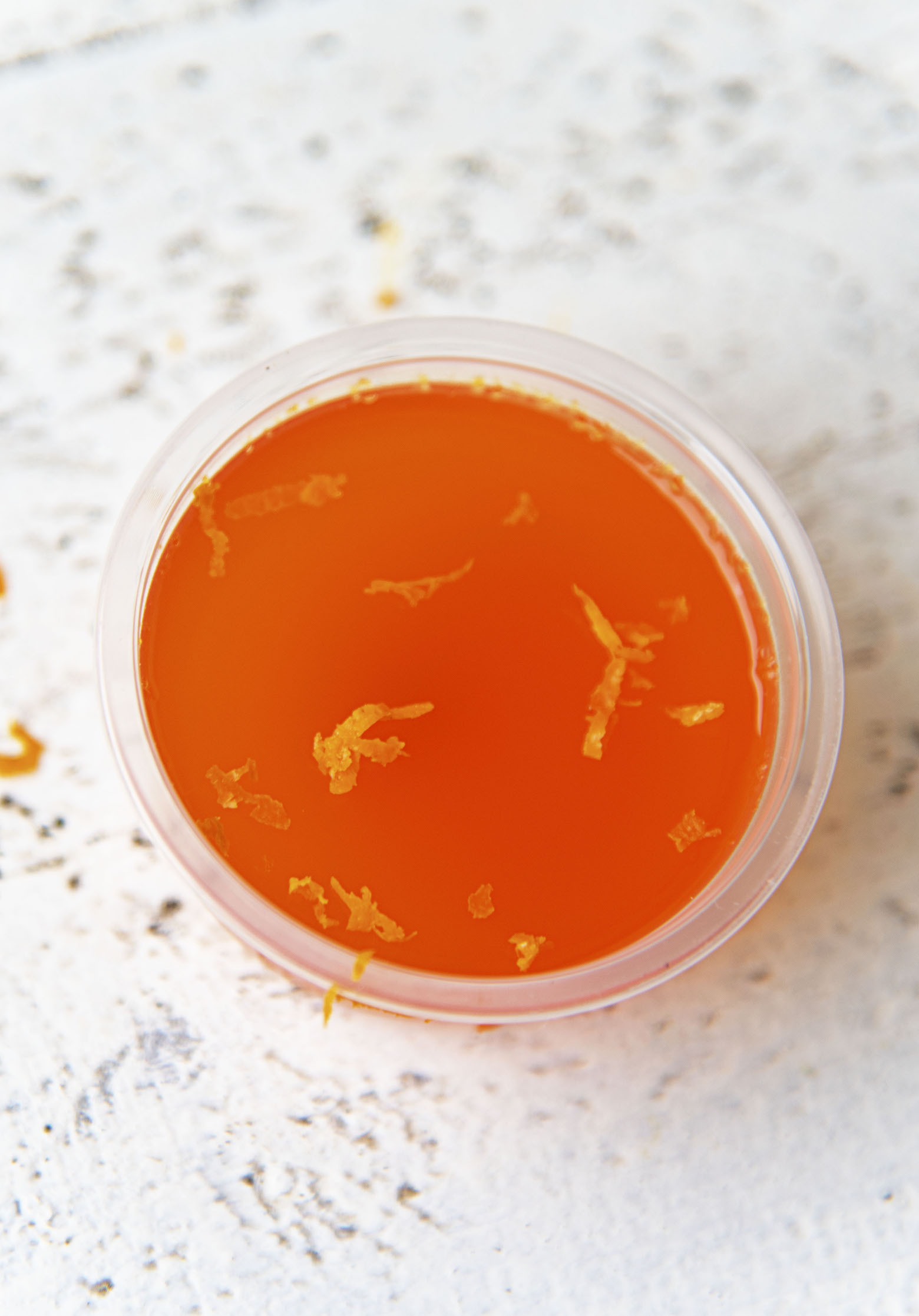 Overhead shot of single jello shot with orange zest.