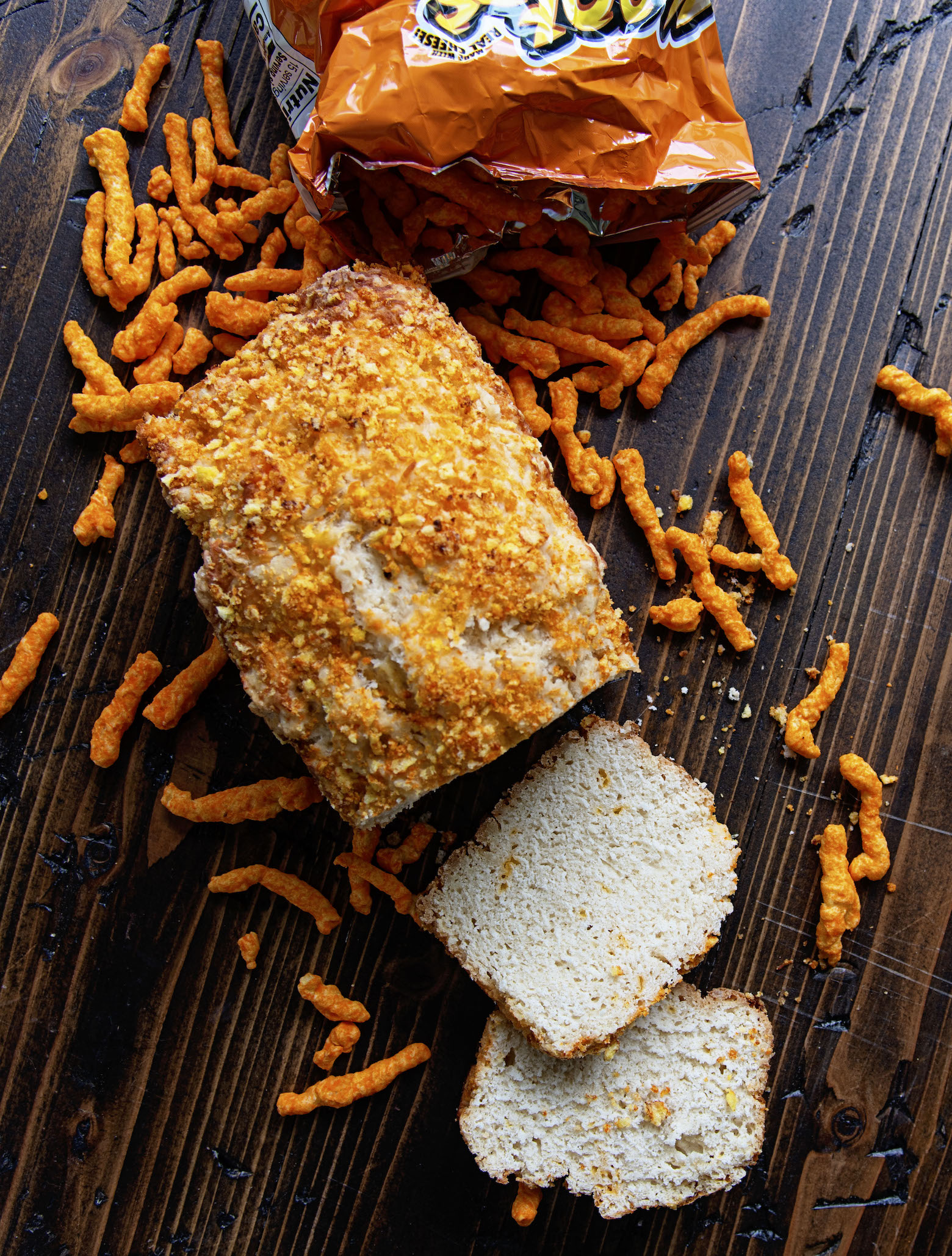 Overhead shot of sliced Cheetos Cheddar Beer Bread  with Cheetos spilling out of a bag. 