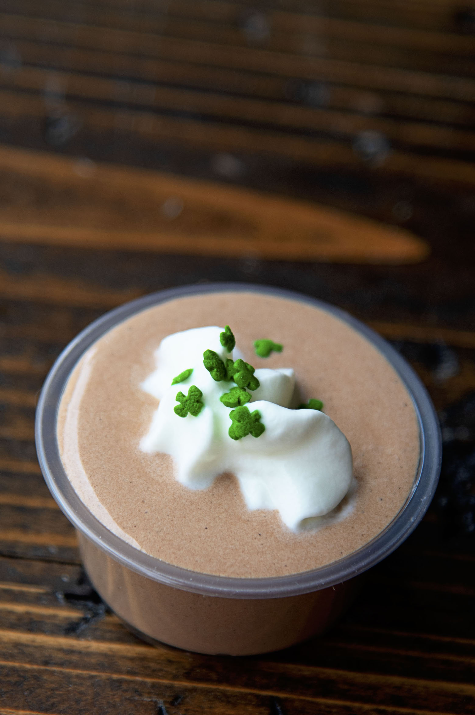 Single Irish Coffee Pudding Shot with focus on the whipped cream and sprinkles.
