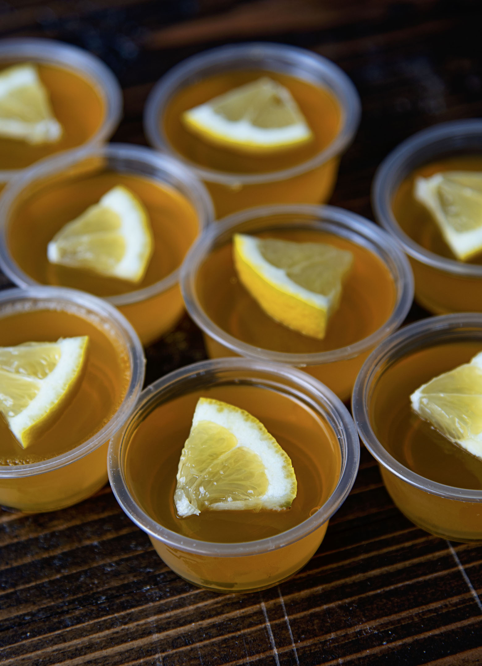 Three quarter shot of several Lynchburg Lemonade Jello Shots with lemon wedges on each one.