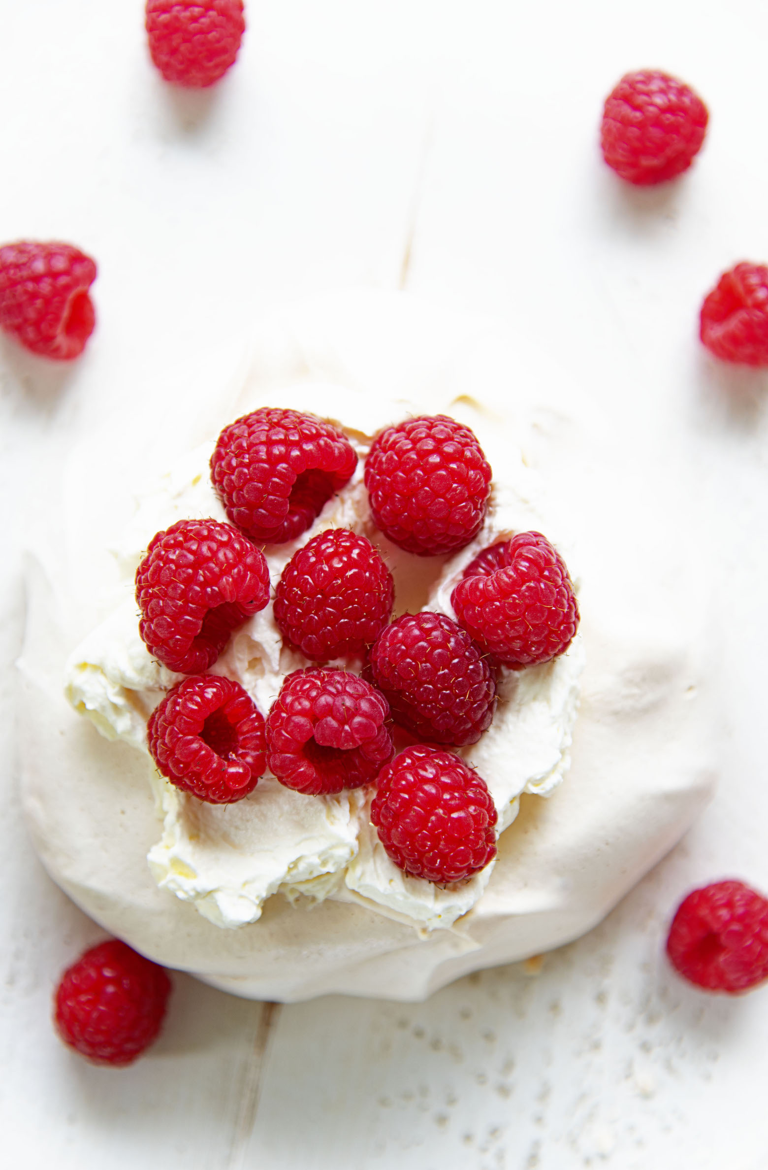 Overhead of single Raspberry Lemon Elderflower Pavlova with focus on the raspberries.