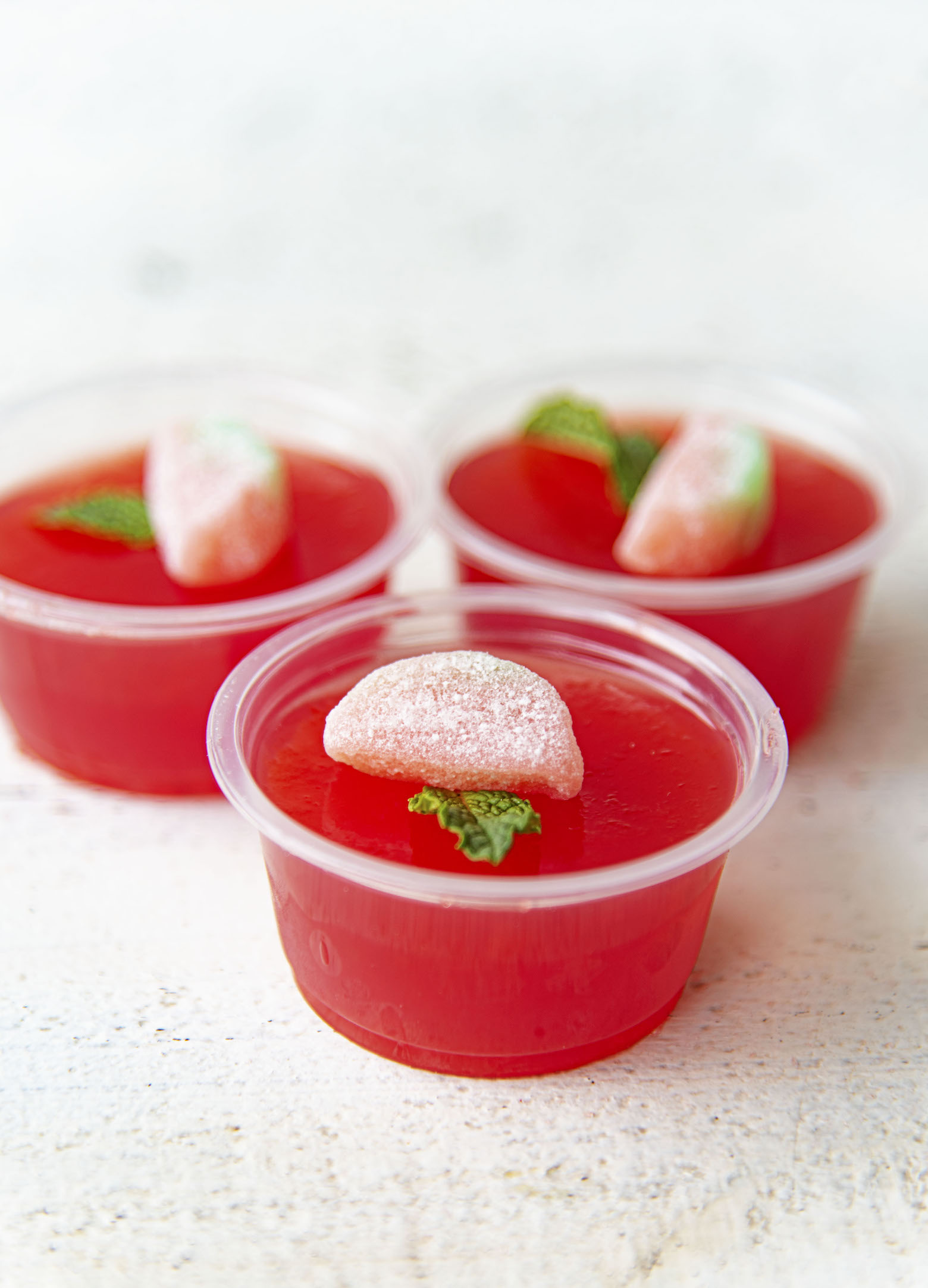 Gathering side view of three Watermelon Mint Julep Jello Shots