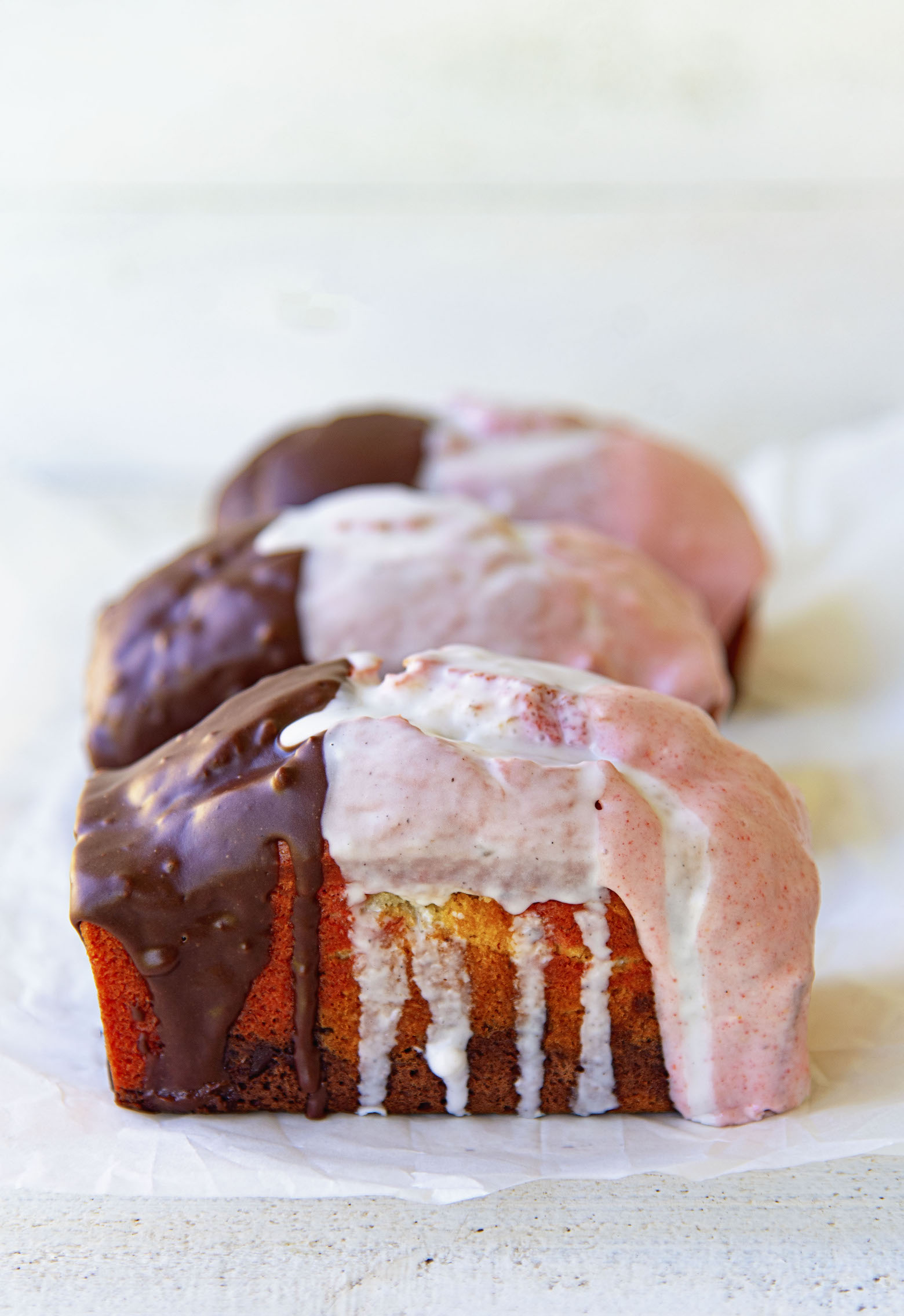 Side view of whole Neapolitan Banana Breads with glaze dripping down