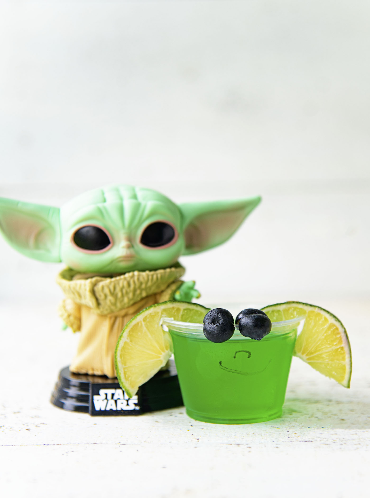 Single Baby Yoda Jello Shot with Grogu figurine behind it.