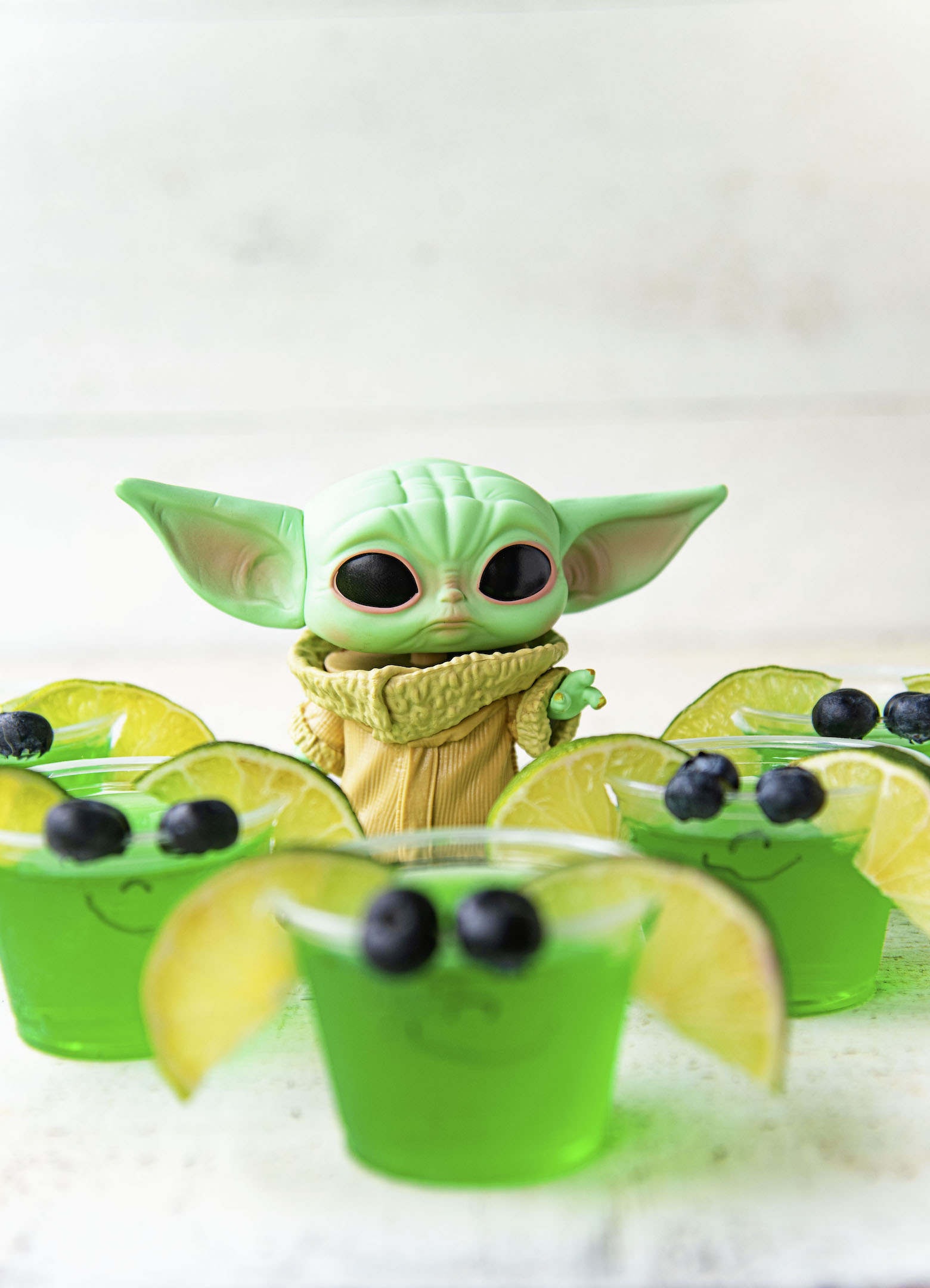 Several blurred jello shots with an in focus Grogu figurine.