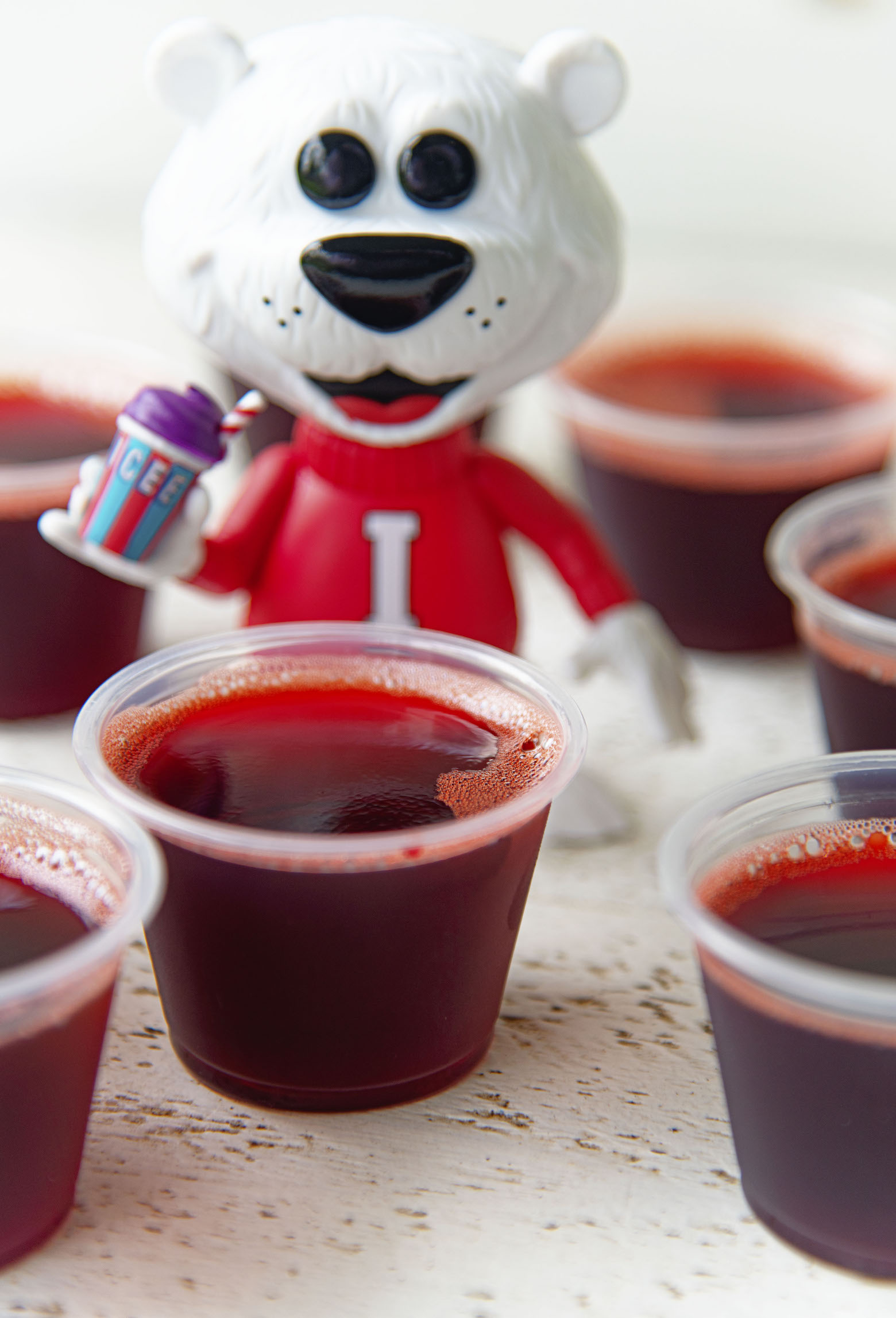 Group of Cherry Cola Icee Jello Shots with the Icee Bear in background