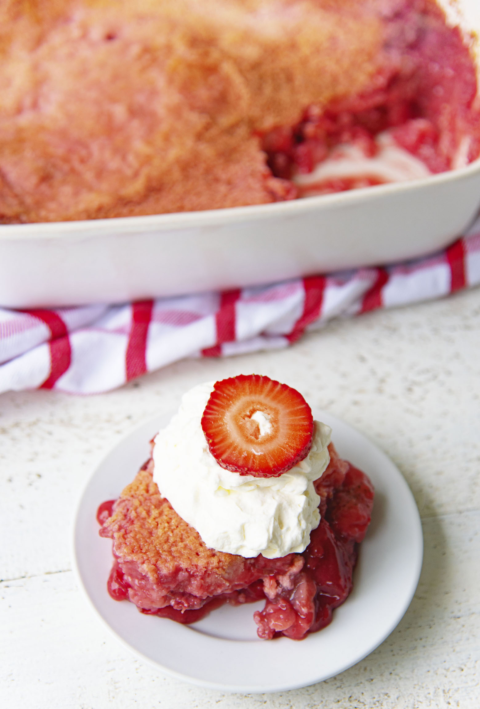 Overhead shot of Strawberry Shortcake Dump Cake on a plate with remaining dump cake in background.