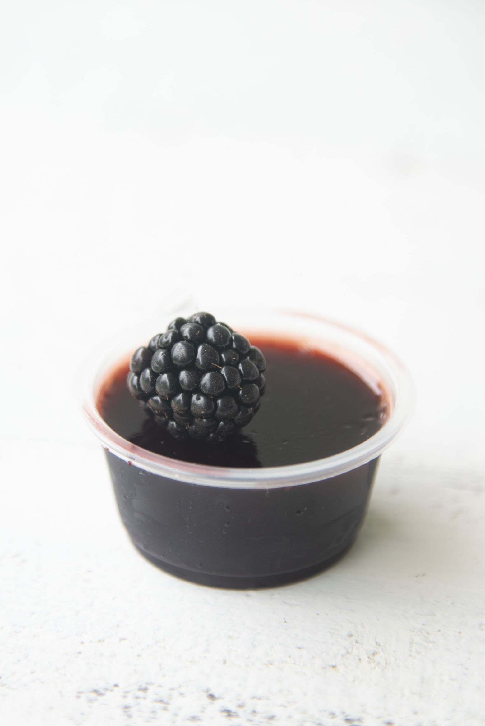 Single jello shot with fresh blackberry on top