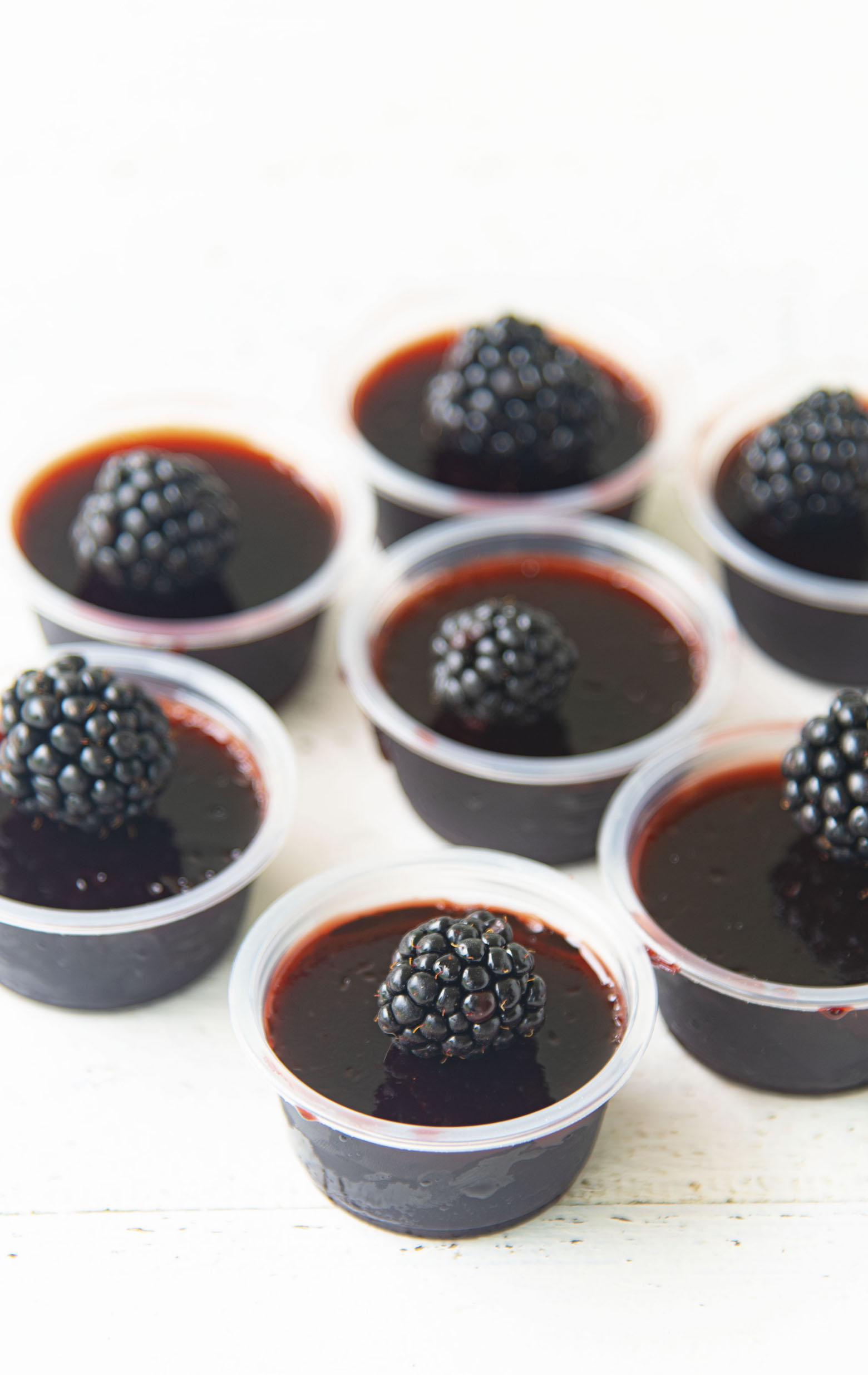 Gathering of Blackberry Bourbon Jello Shots all with fresh blackberries on top