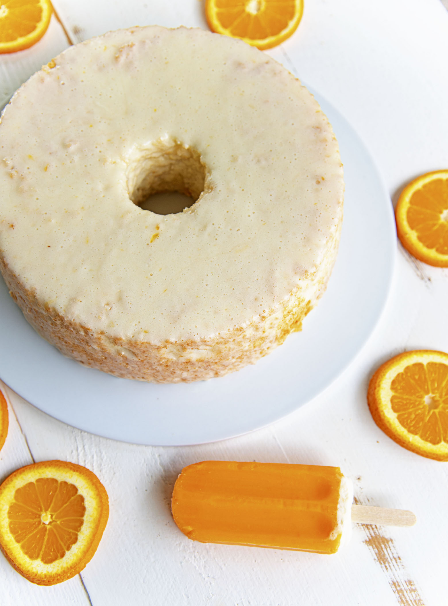 Overhead shot of Creamsicle Angel Food Cake with orange slices and a creamsicle. 