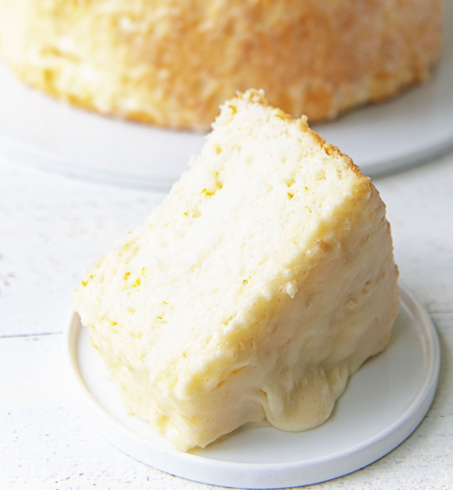 Slice of Creamsicle Angel Food Cake on a plate with icing dripping down