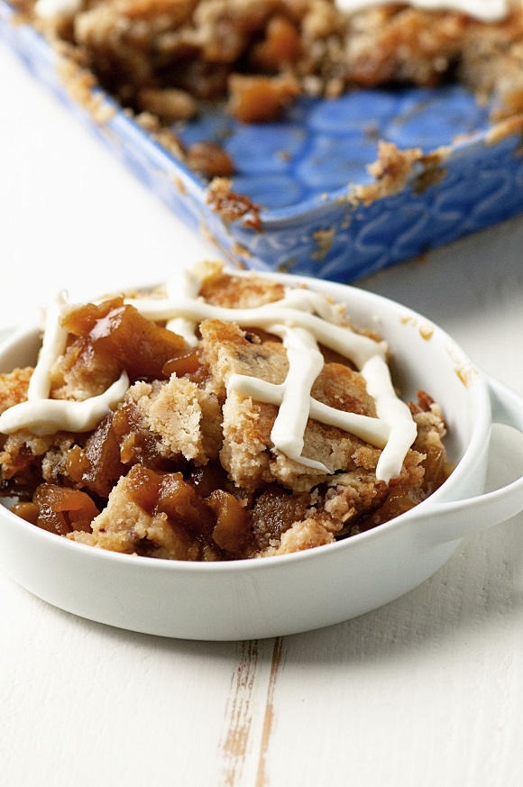 Side view of Apple Cinnamon Bun Cookie Cobbler in a bowl with remaining cobbler behind it. 