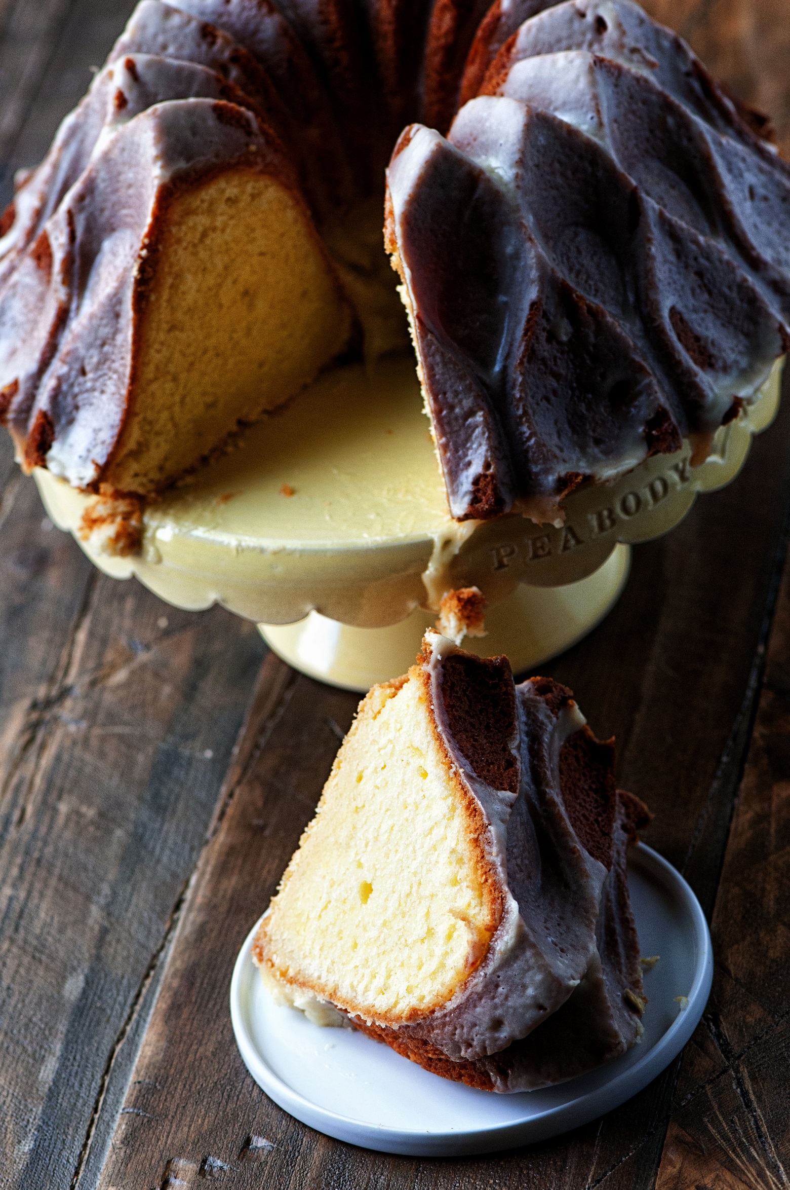 Cake on a cake stand with missing slice of cake on a small plate sitting in front of it. 