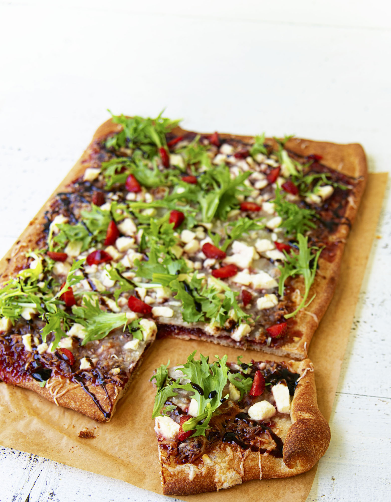 Three quarter shot of the flatbread with a piece cut out and moved to the side of the flatbread. 